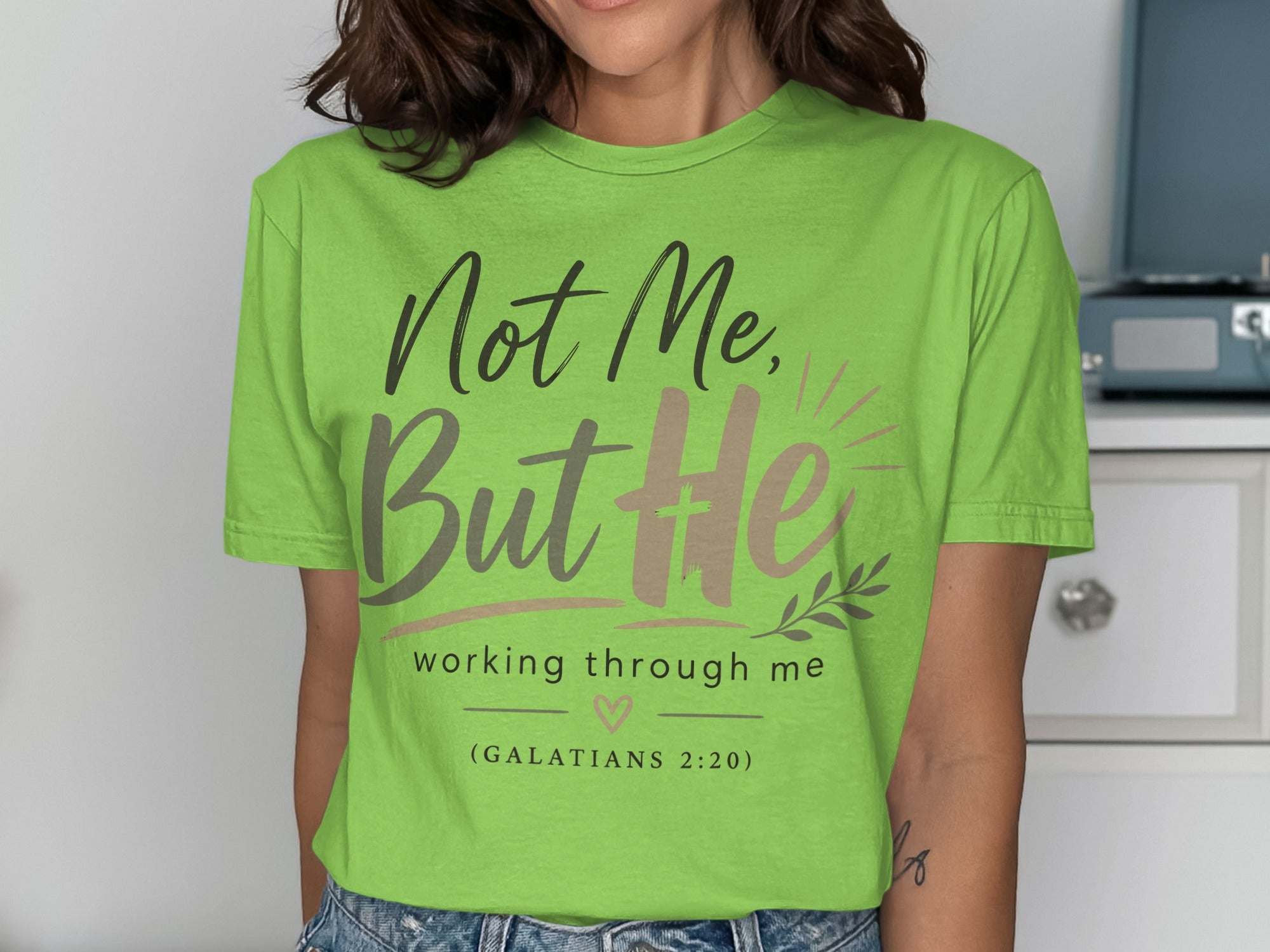 Green t-shirt with "Not Me, But He working through me" and Bible verse.