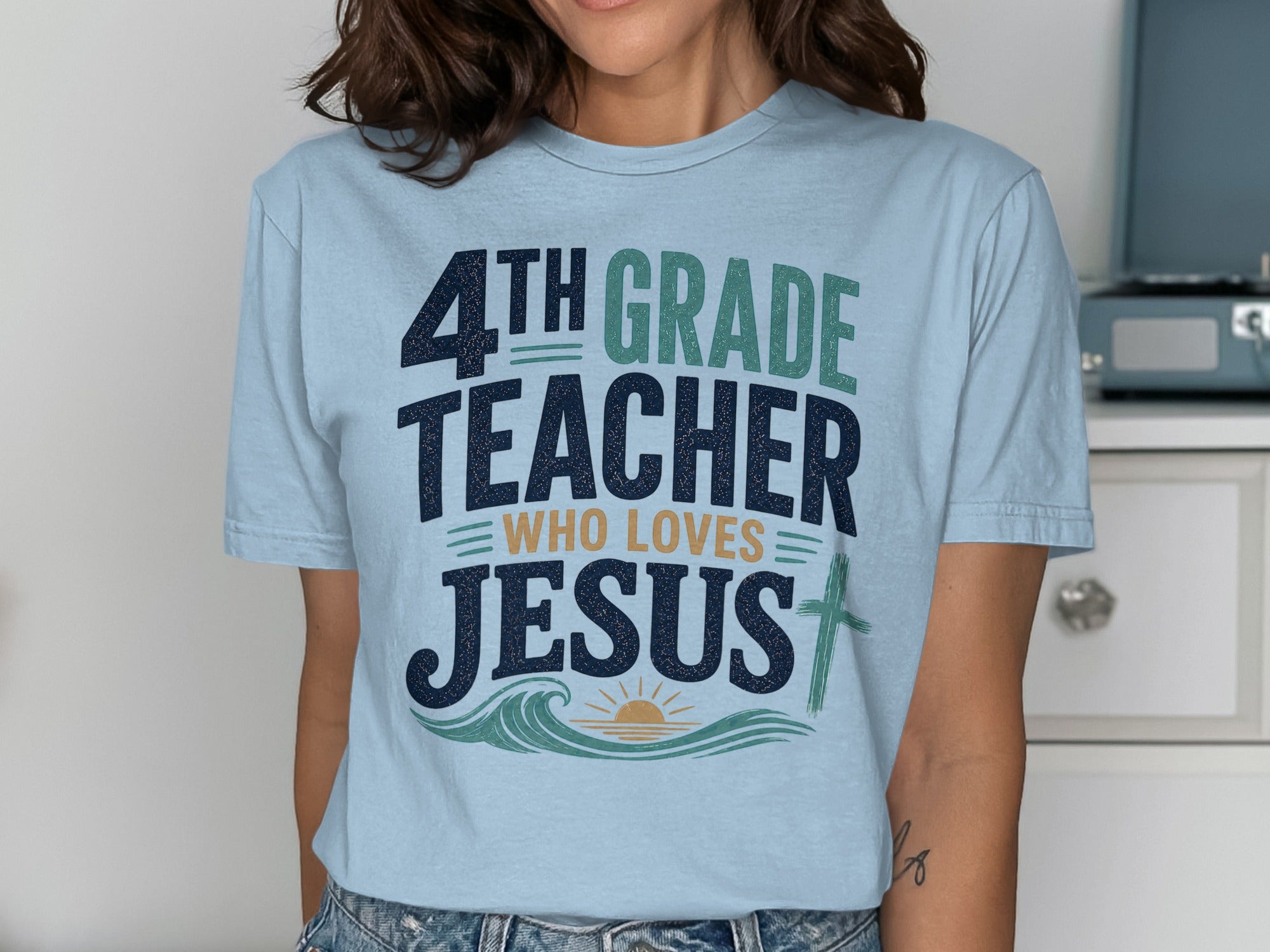 Light blue t-shirt with "4TH GRADE TEACHER WHO LOVES JESUS" text and cross design.