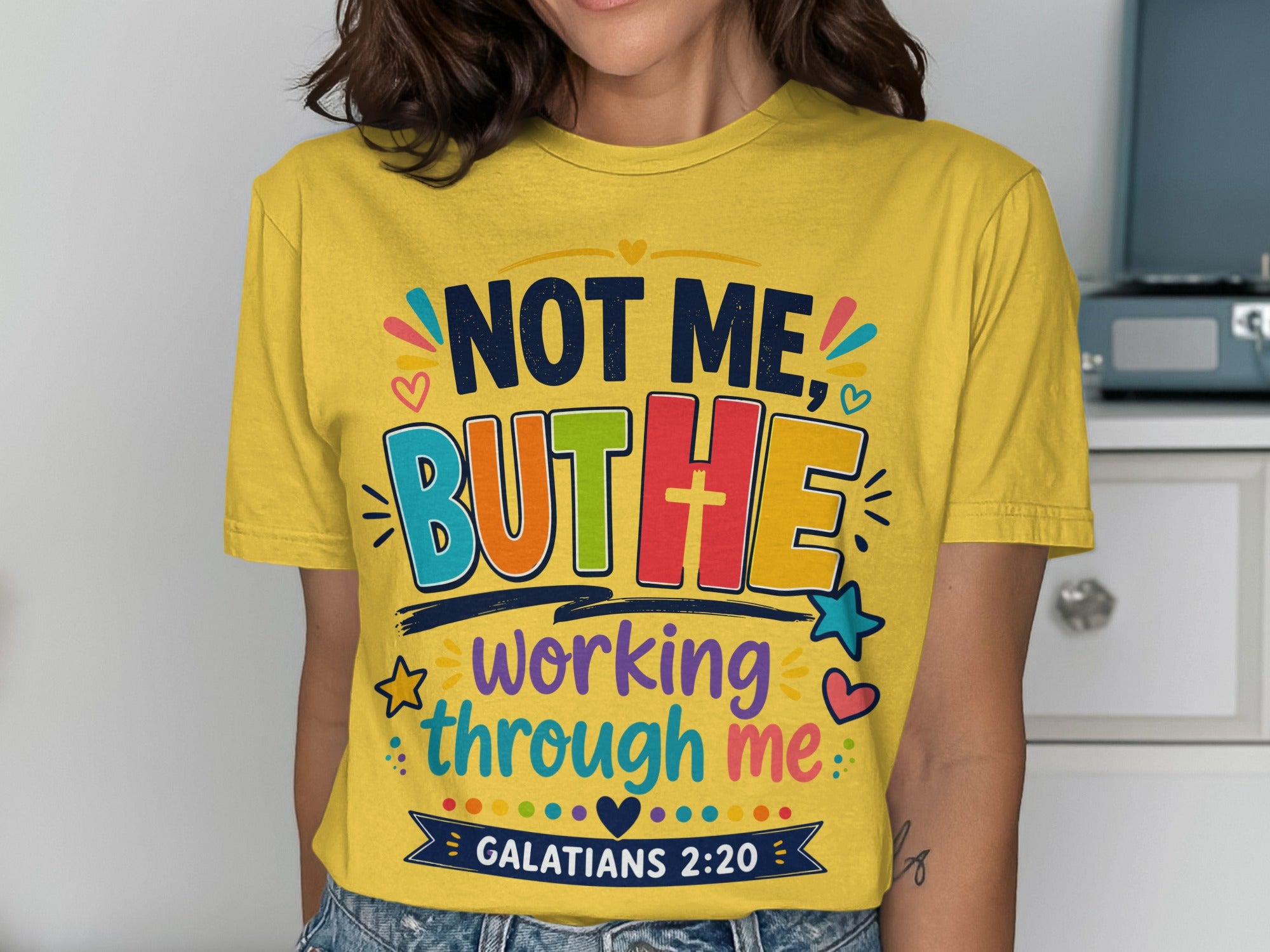 Yellow t-shirt with colorful "NOT ME, BUT HE working through me" text and Galatians 2:20.