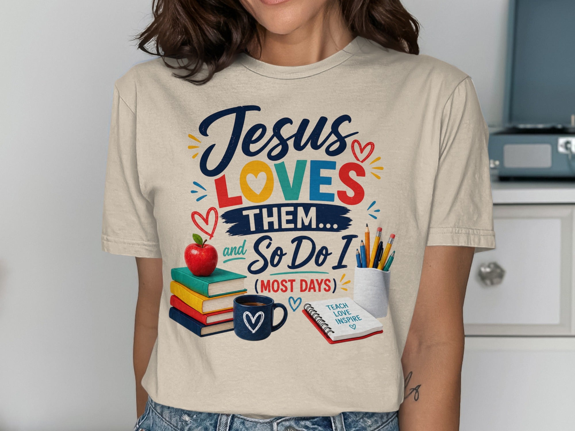T-shirt with "Jesus Loves Them... And So Do I (Most Days)" text and school supplies.