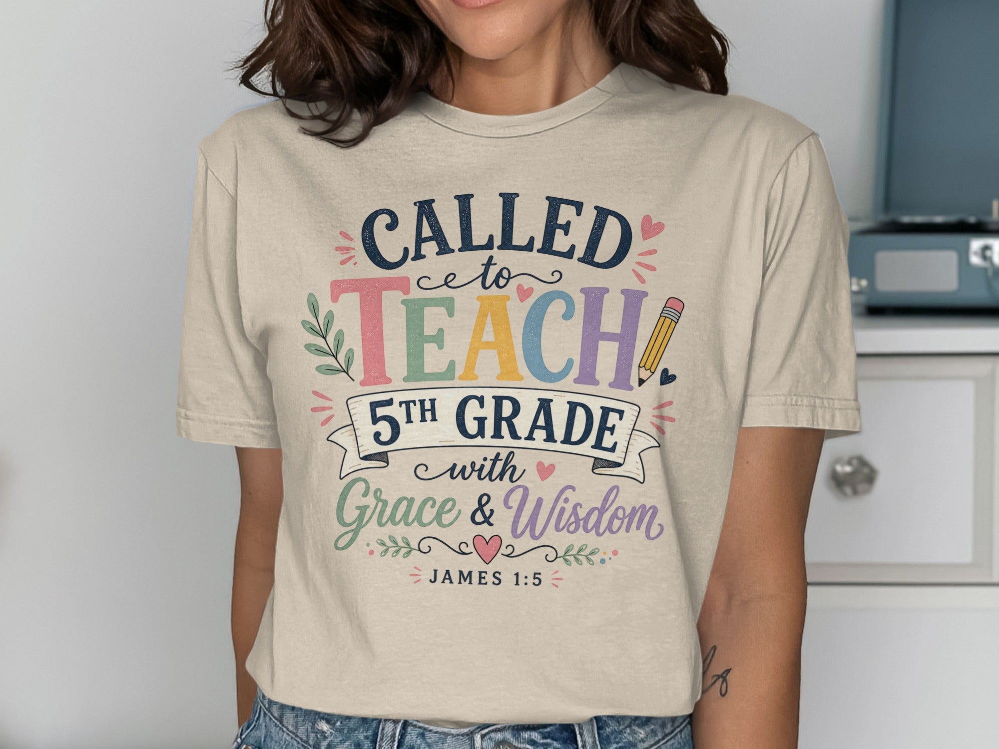 "Called to Teach 5th Grade with Grace and Wisdom" text on a beige t-shirt.