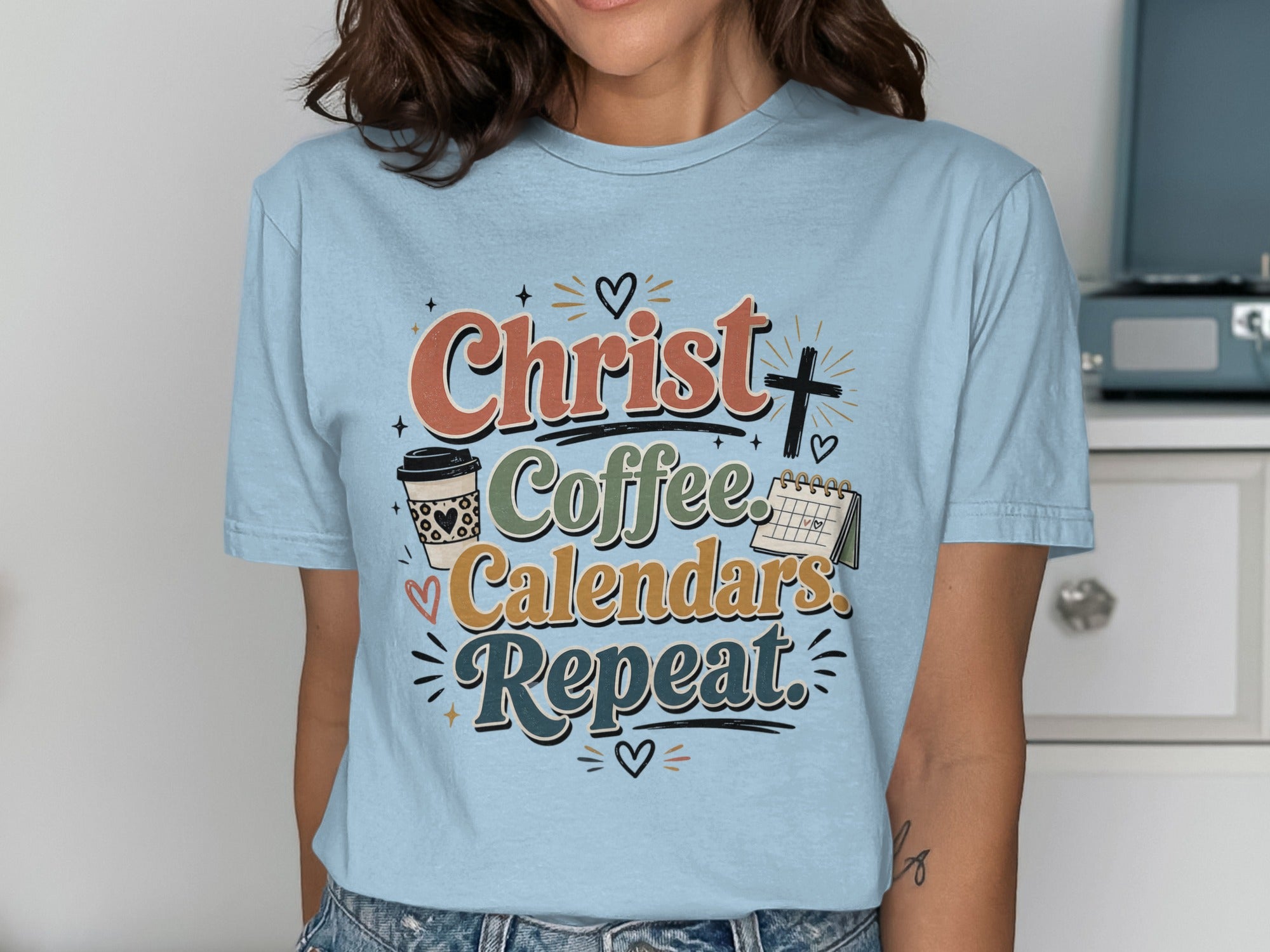 Light blue t-shirt with "Christ. Coffee. Calendars. Repeat." slogan and calendar graphic.