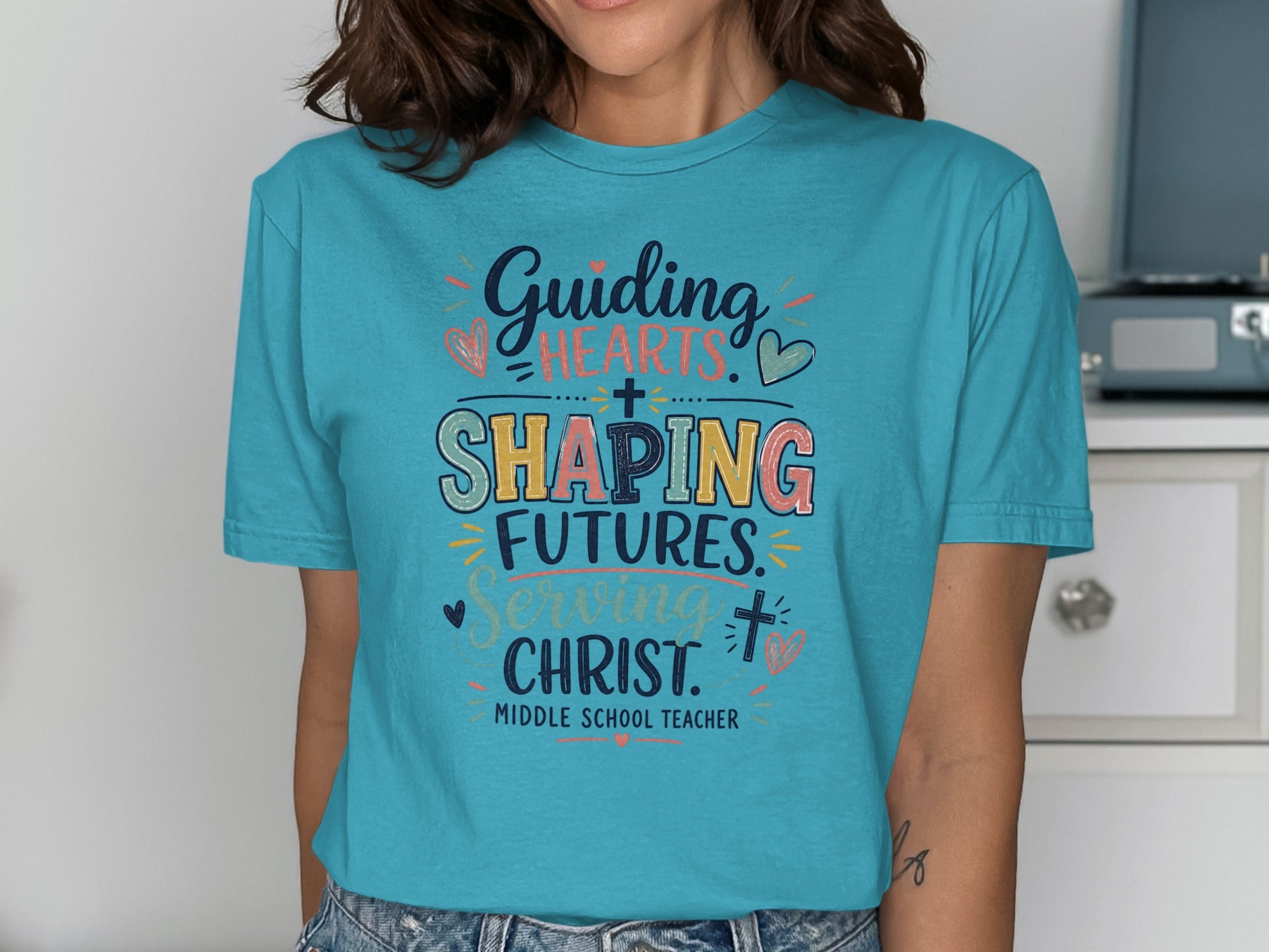 Teal t-shirt with "Guiding Hearts, Shaping Futures, Serving Christ" and "Middle School Teacher" text.