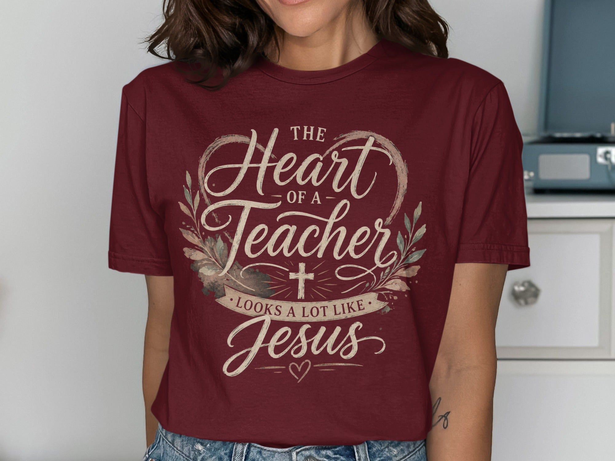 Maroon t-shirt with "The heart of a teacher looks a lot like Jesus" text and floral accents.