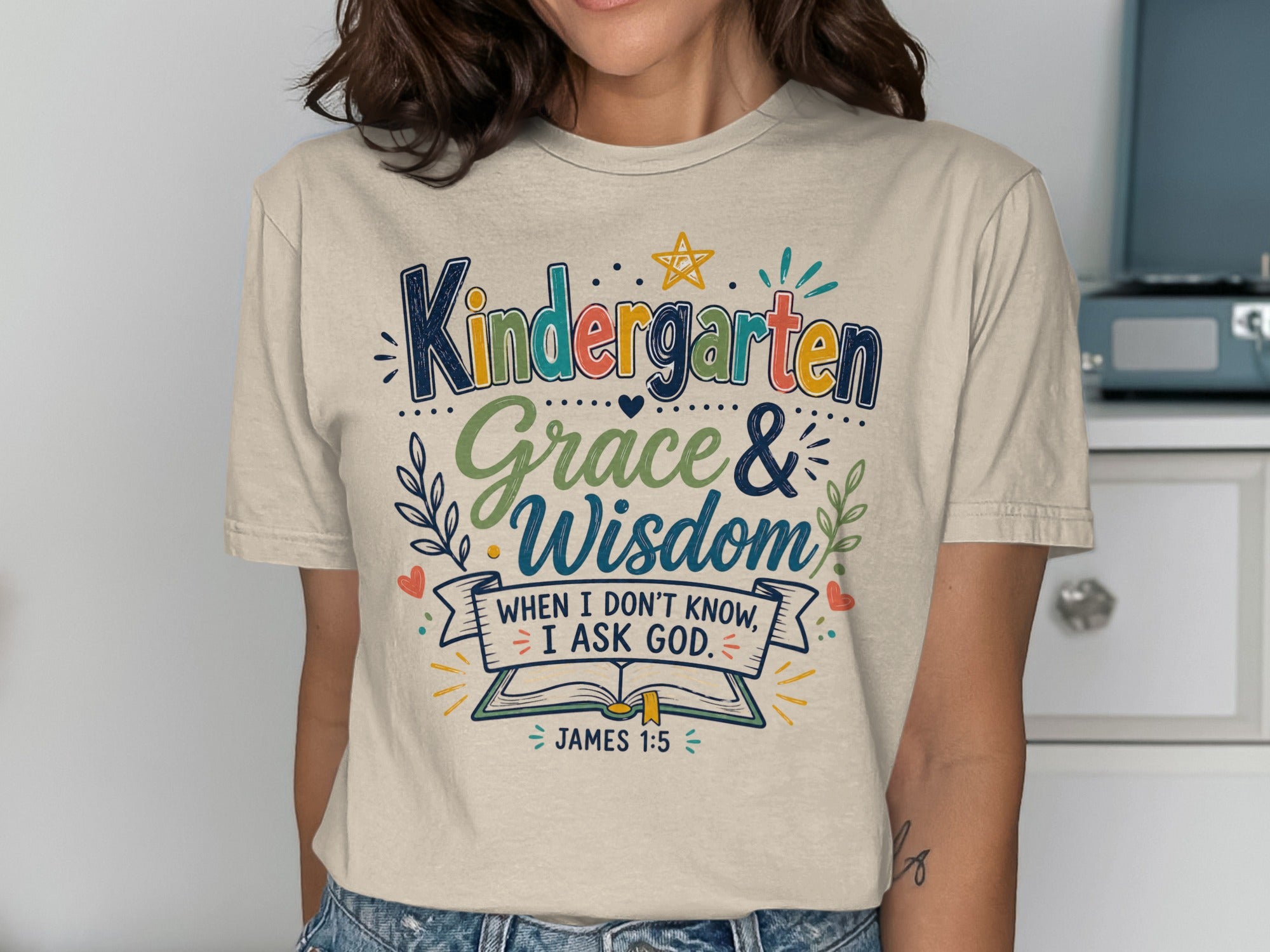 "Kindergarten Grace & Wisdom" text with Bible verse James 1:5 on a cream t-shirt.