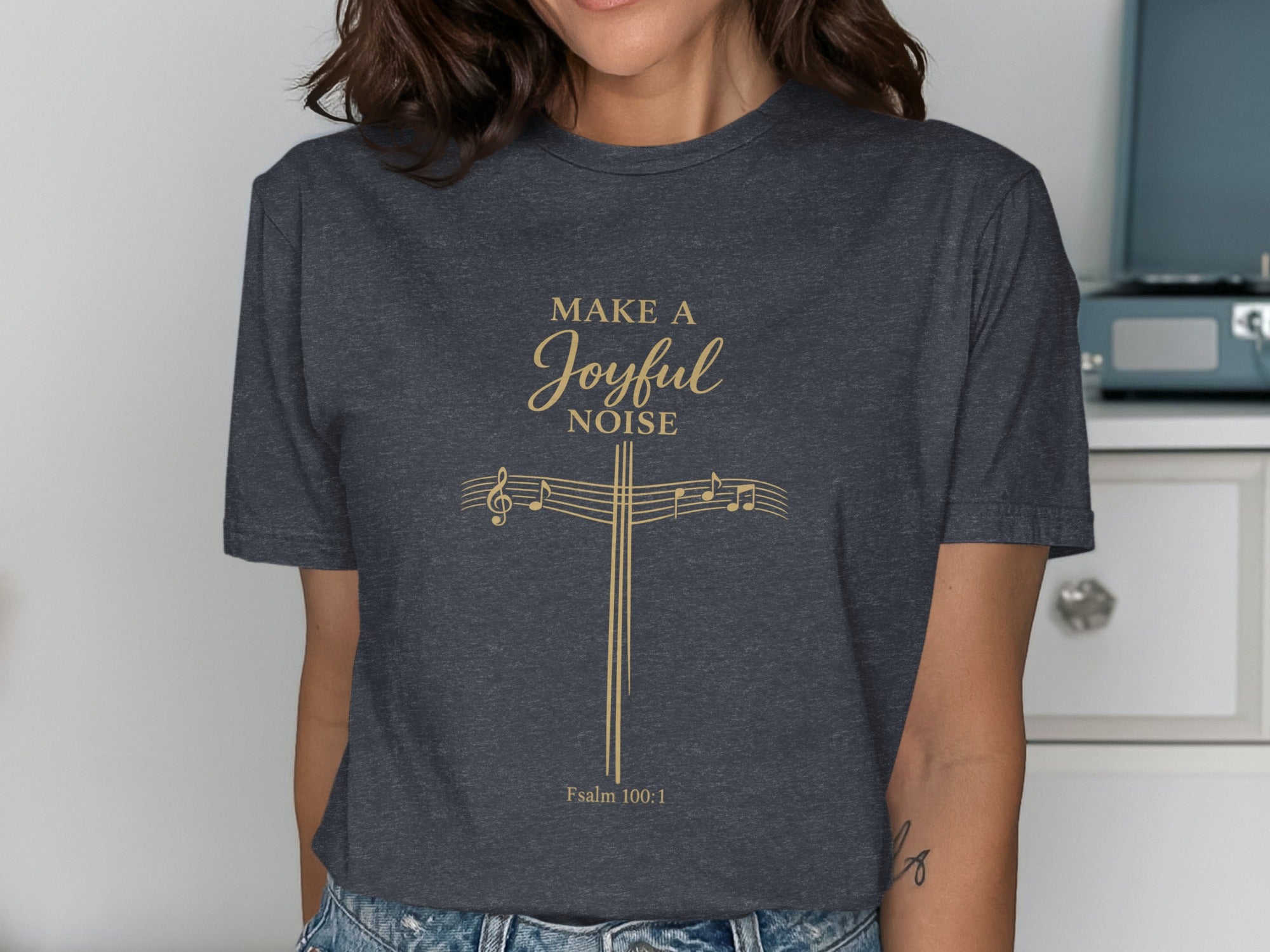 Dark t-shirt with "Make a Joyful Noise" and musical notes above a cross.