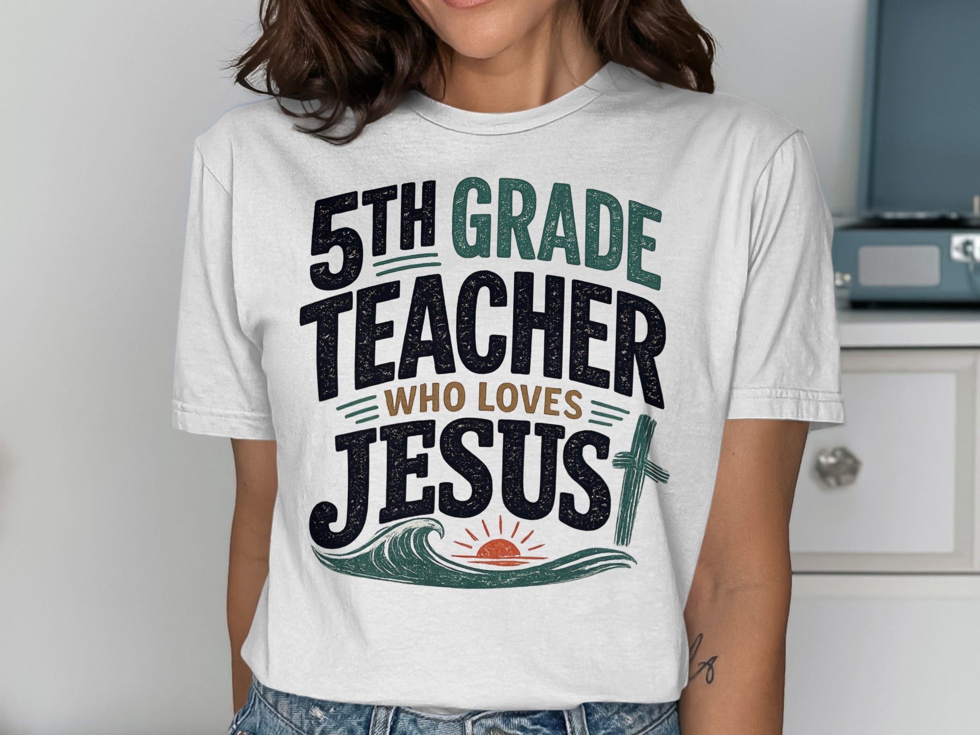 White t-shirt with "5th Grade Teacher Who Loves Jesus" text and a cross.