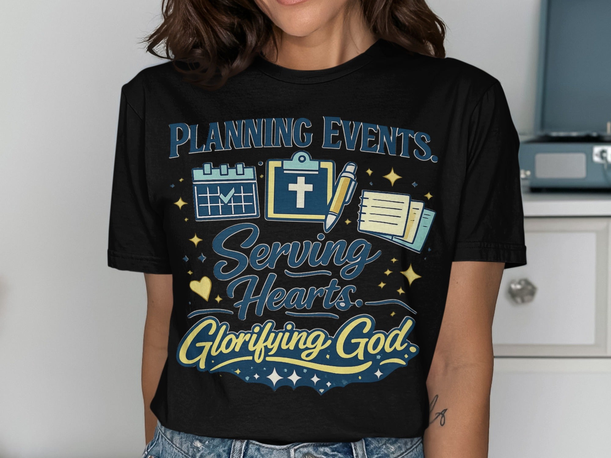 Black t-shirt with "Planning Events. Serving Hearts. Glorifying God." and icons.