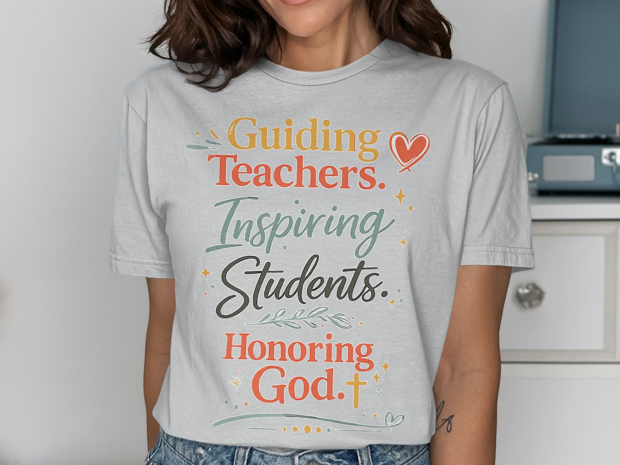 T-shirt with "Guiding Teachers. Inspiring Students. Honoring God." text and floral accents.