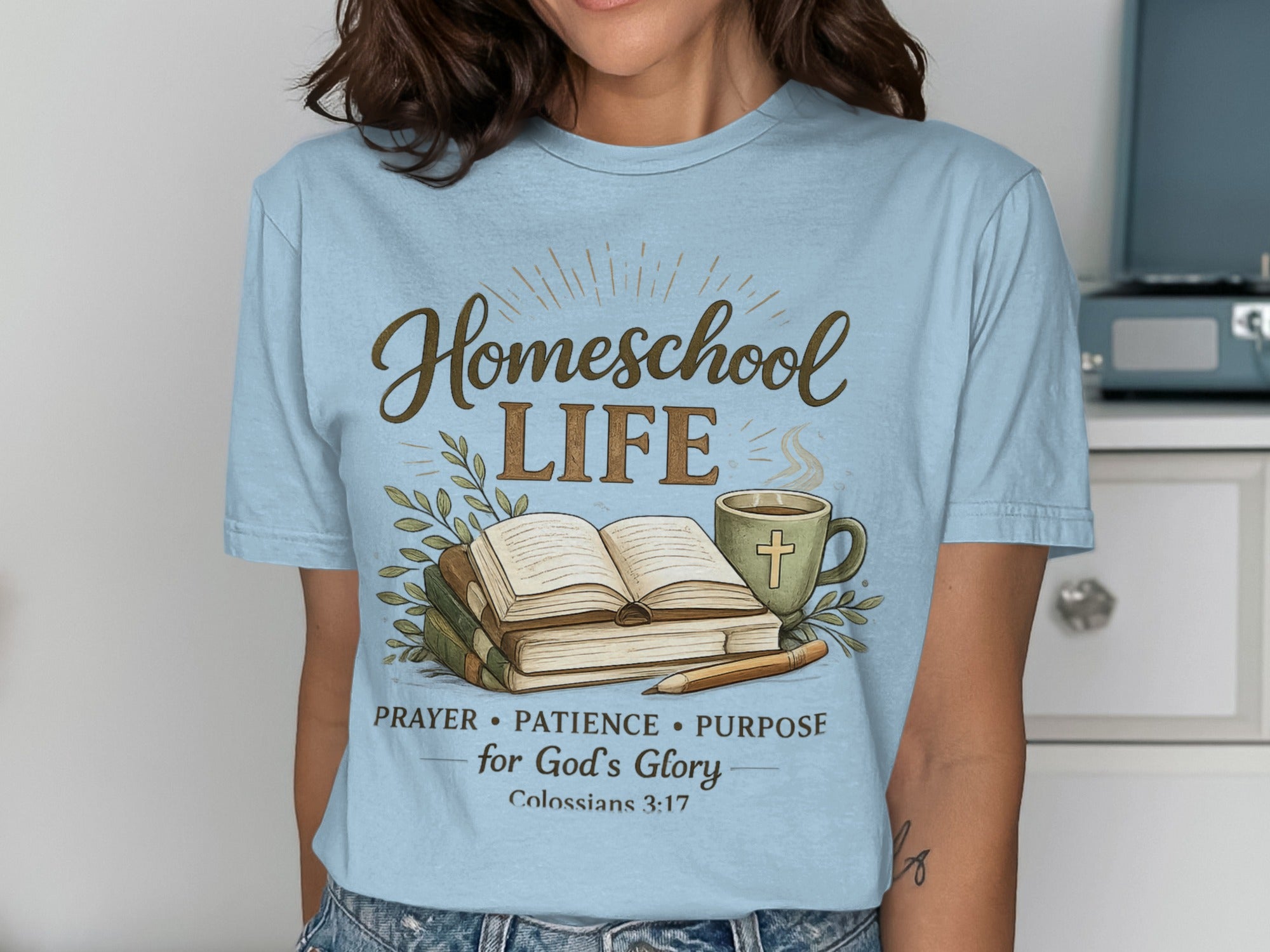 Light blue t-shirt with "Homeschool Life" text, books, coffee mug, and Bible verse.