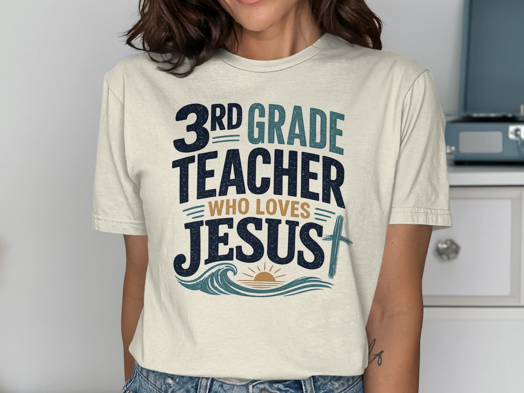 3rd Grade Teacher Who Loves Jesus t-shirt with wave and sun design.