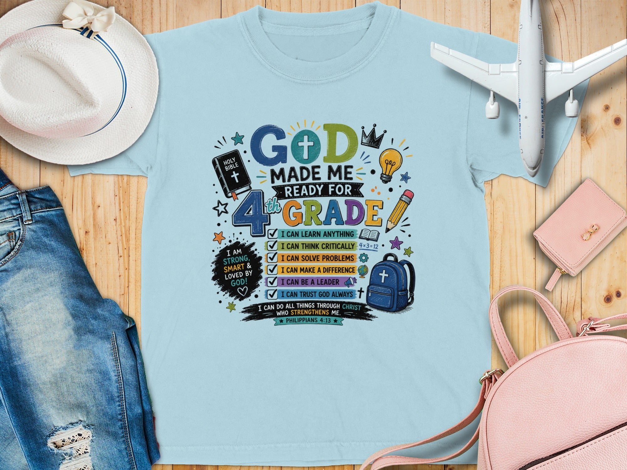 "God Made Me Ready for 4th Grade" text on a light blue t-shirt with graphics.