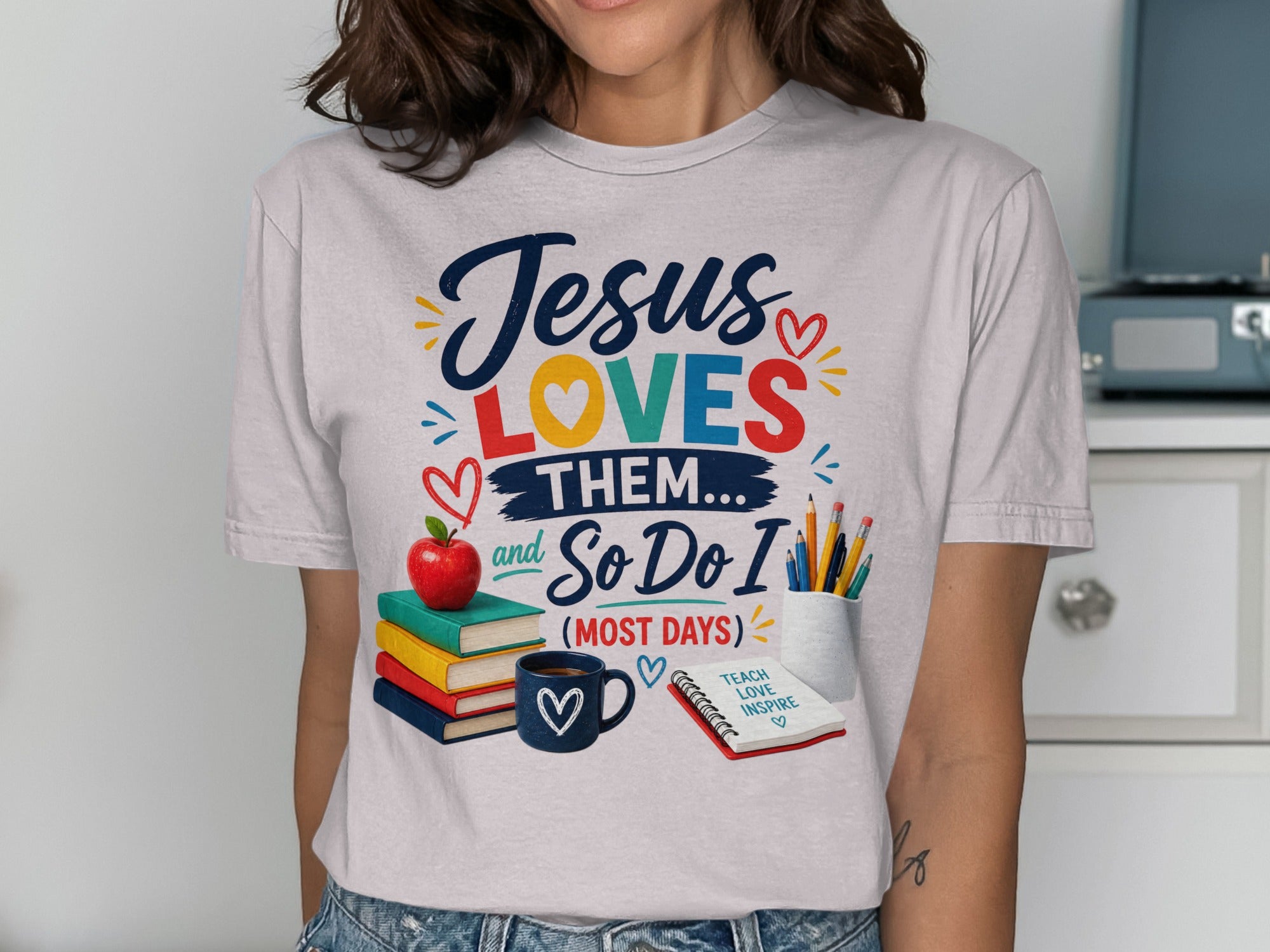 T-shirt with "Jesus LOVES THEM... and So Do I (MOST DAYS)" text, apple, books, mug, and pencils.