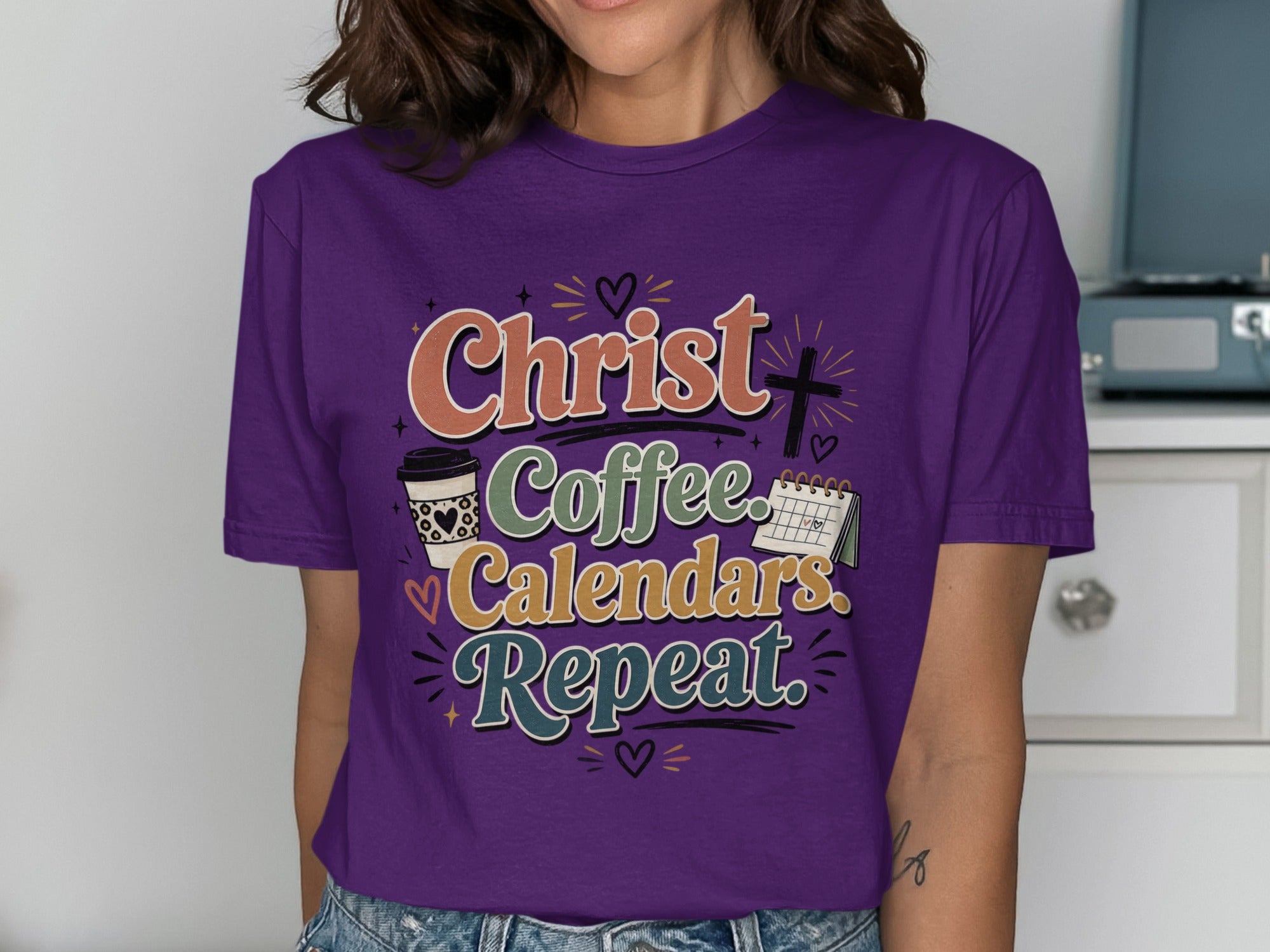 Purple t-shirt with "Christ. Coffee. Calendars. Repeat." text and illustrations.
