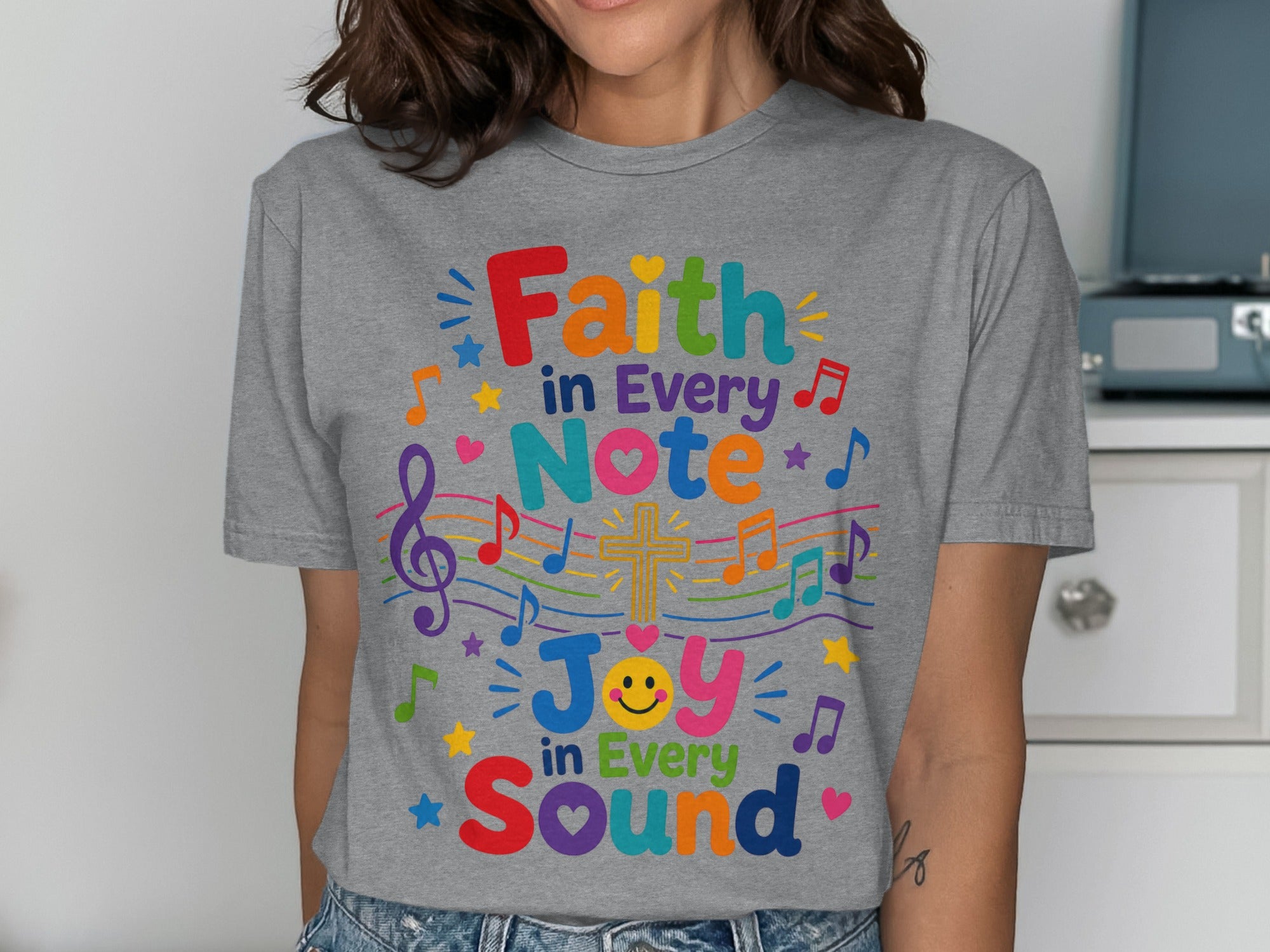 Grey t-shirt with colorful text "Faith in Every Note, Joy in Every Sound" and musical accents.