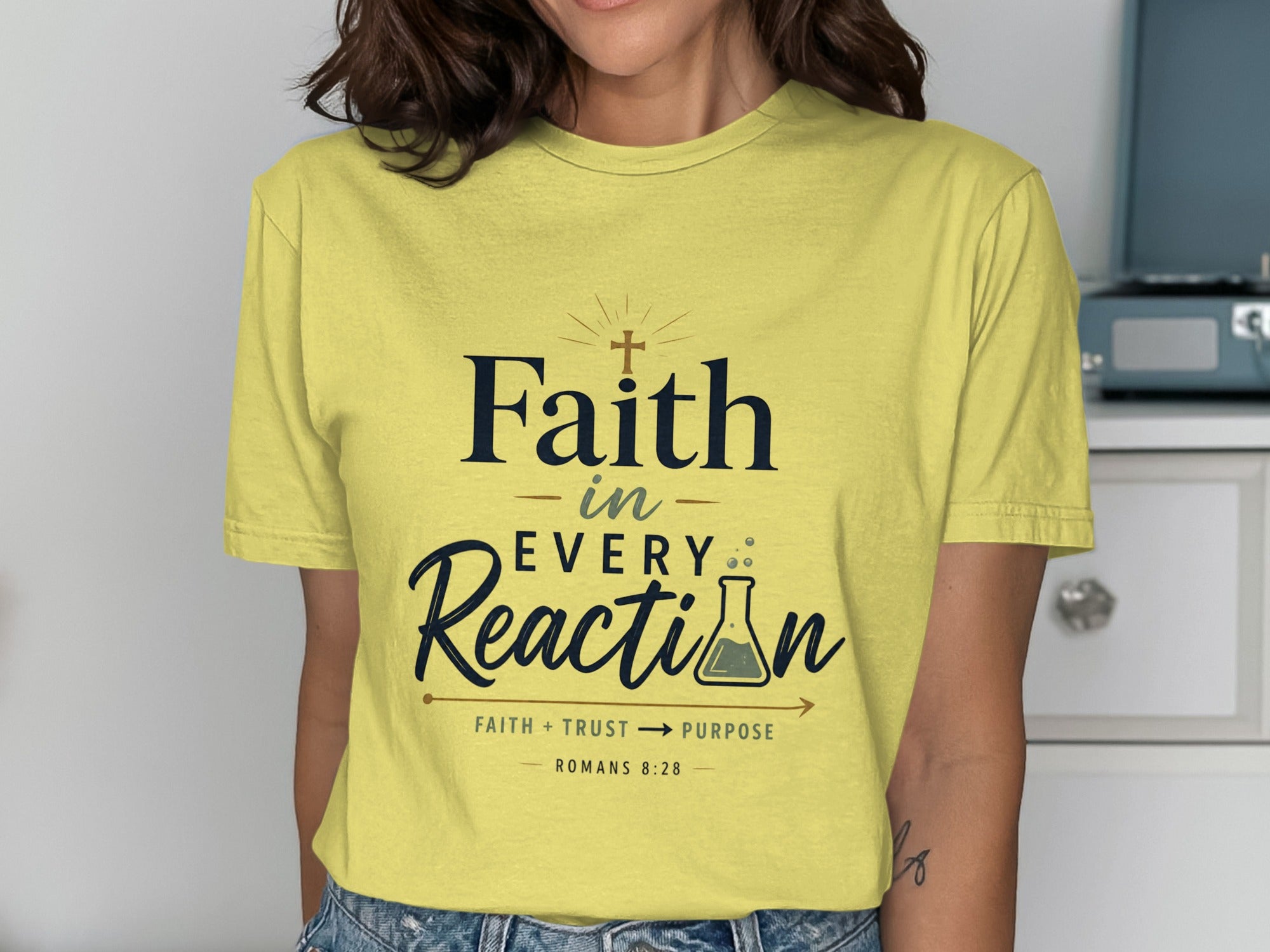Yellow t-shirt with "Faith in Every Reaction" and Bible verse Romans 8:28.