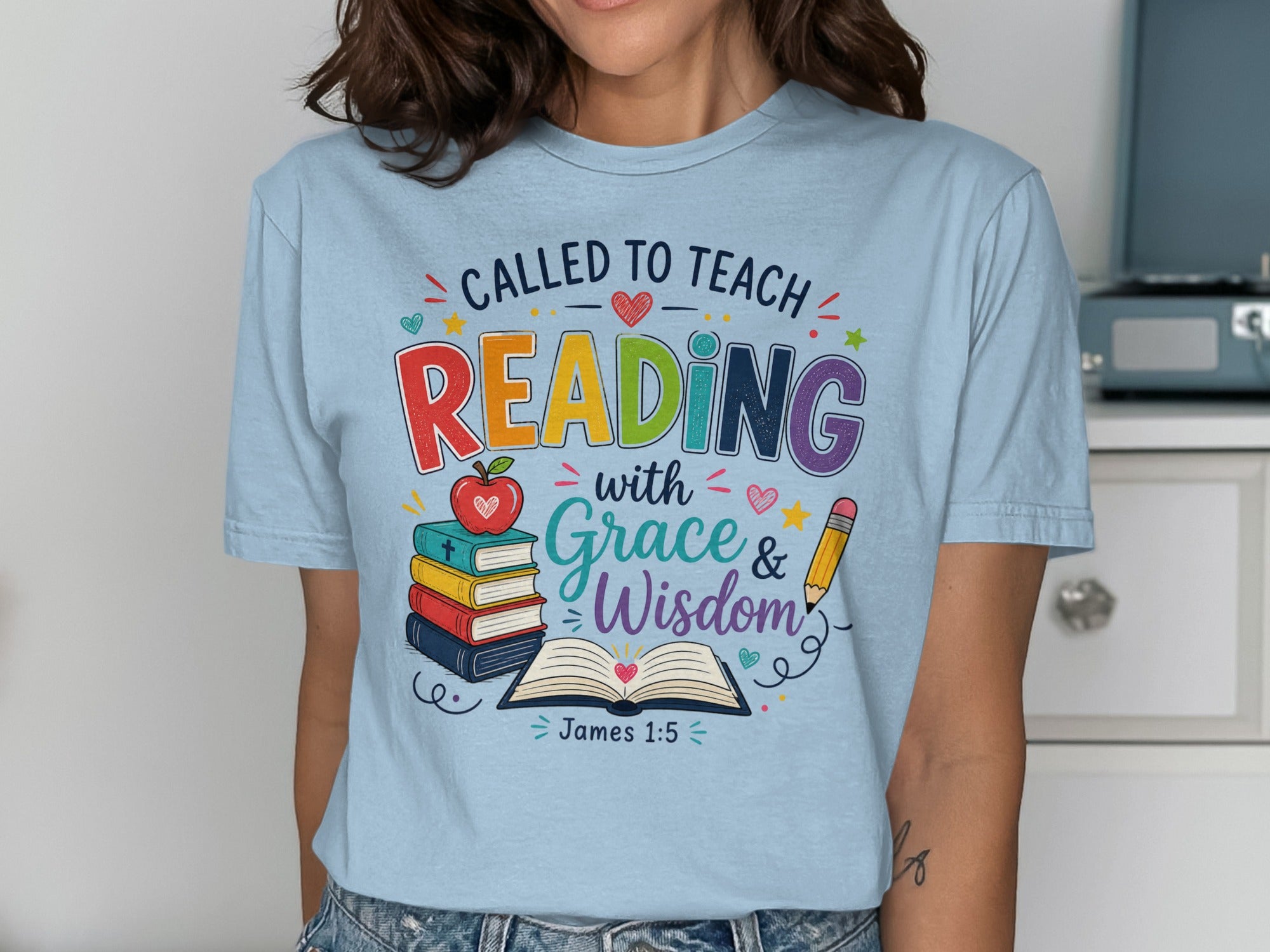 T-shirt with "Called to Teach Reading with Grace & Wisdom, James 1:5" and books.