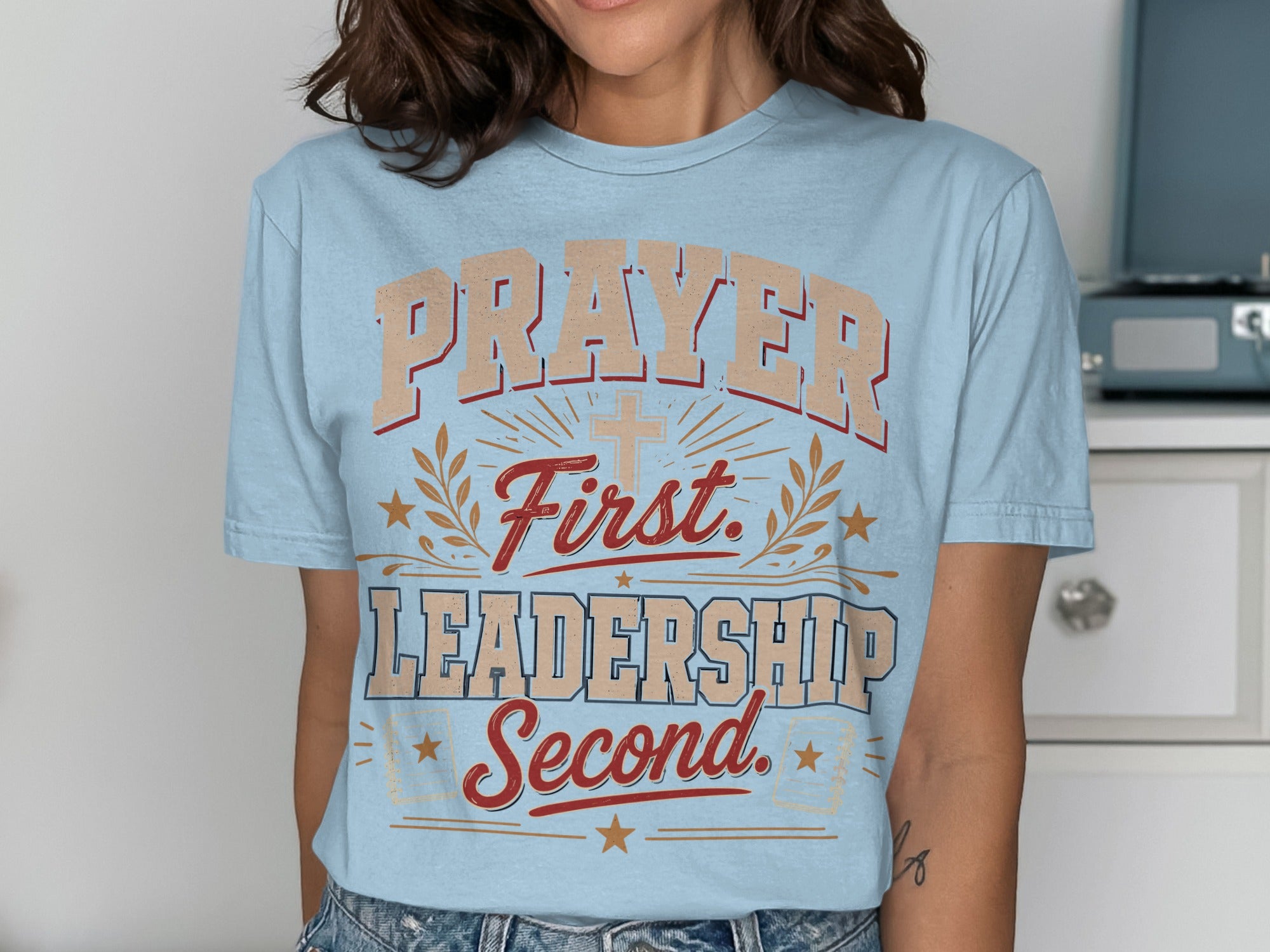 Light blue t-shirt with "Prayer First. Leadership Second." text and a cross.