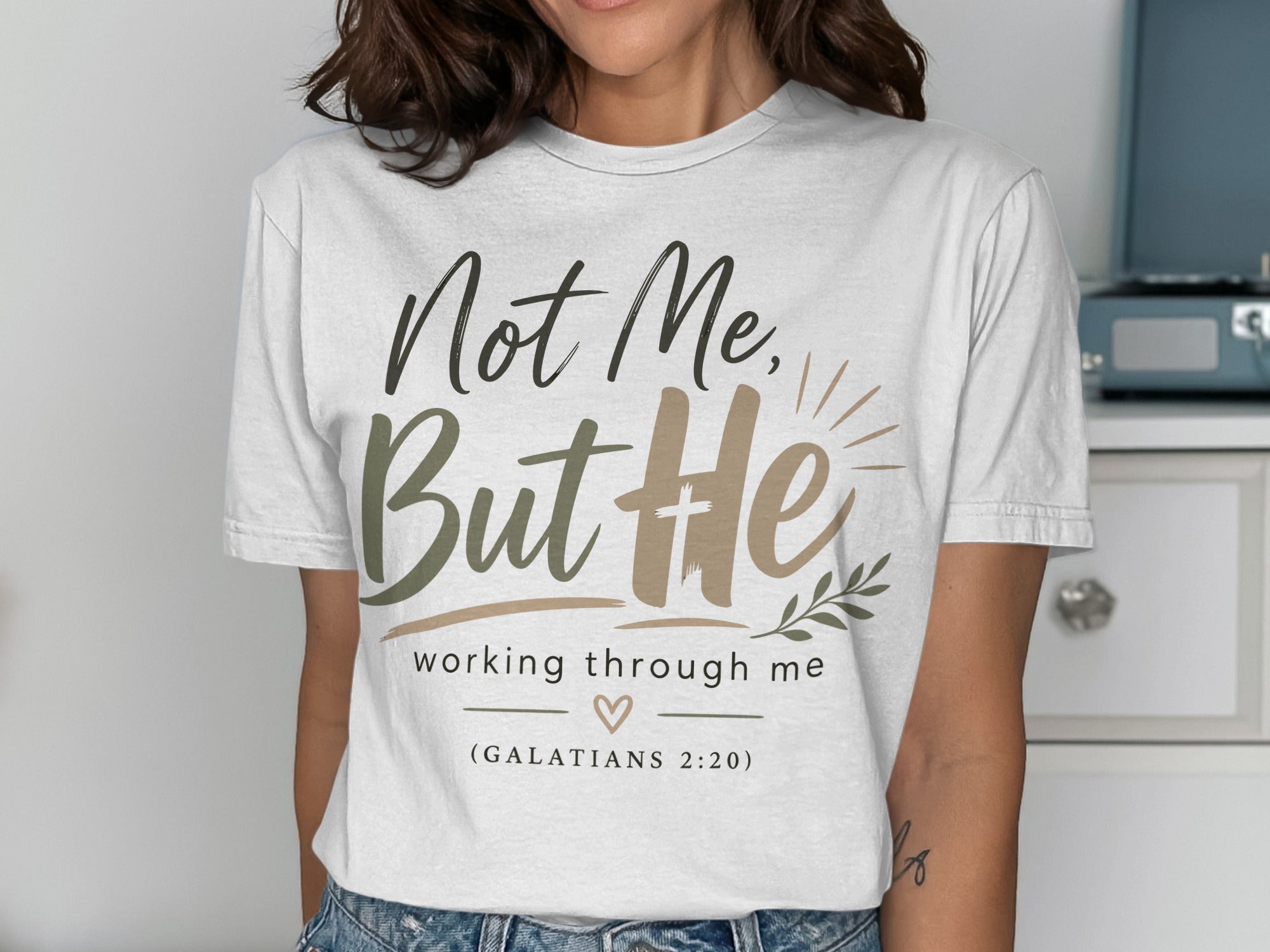 White t-shirt with "Not Me, But He" and "working through me" text.