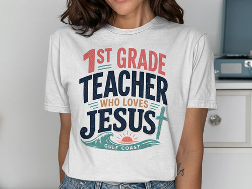 White t-shirt with "1st Grade Teacher Who Loves Jesus" text and ocean graphic.