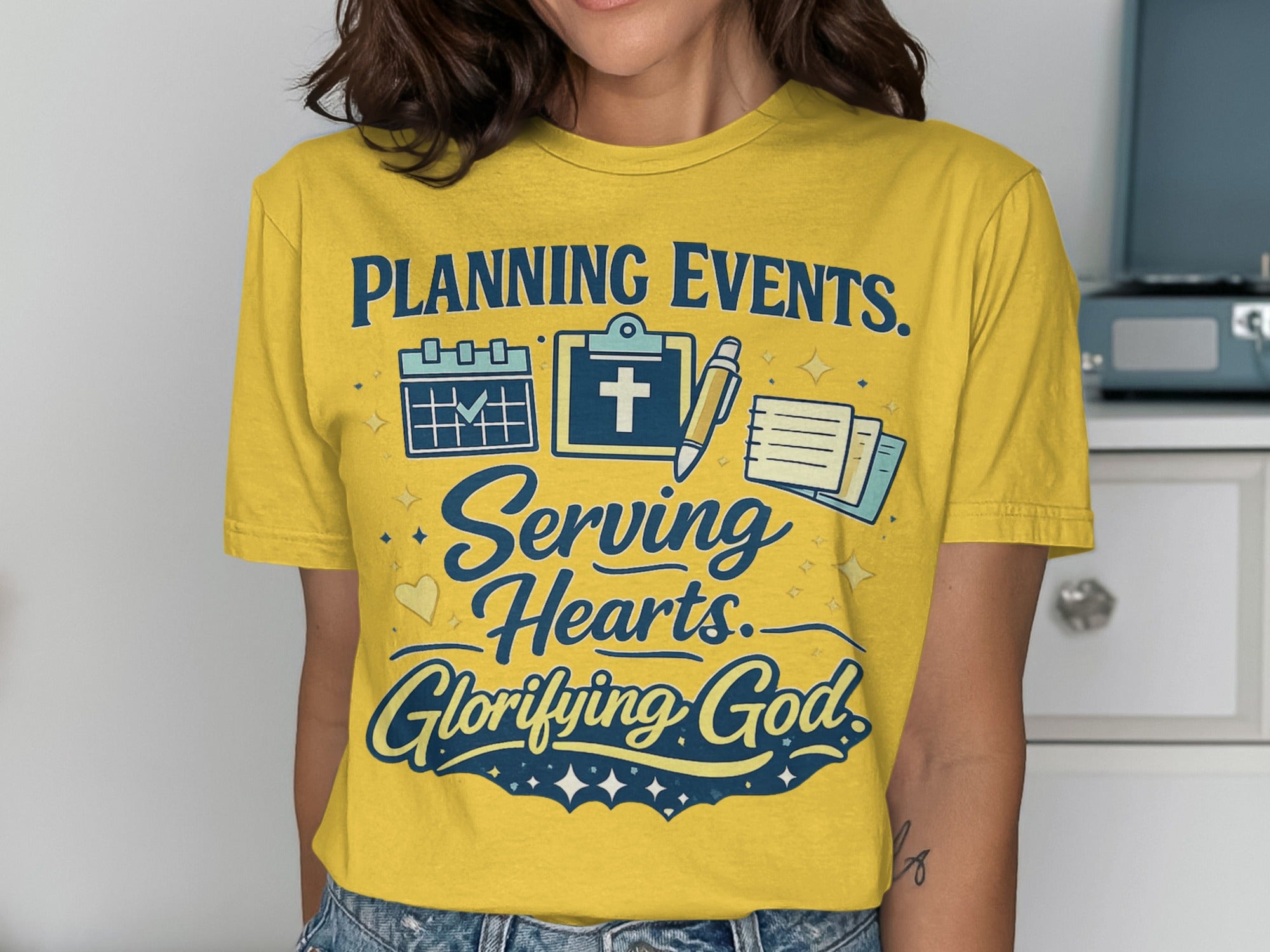 Yellow t-shirt with "Planning Events. Serving Hearts. Glorifying God." and icons.