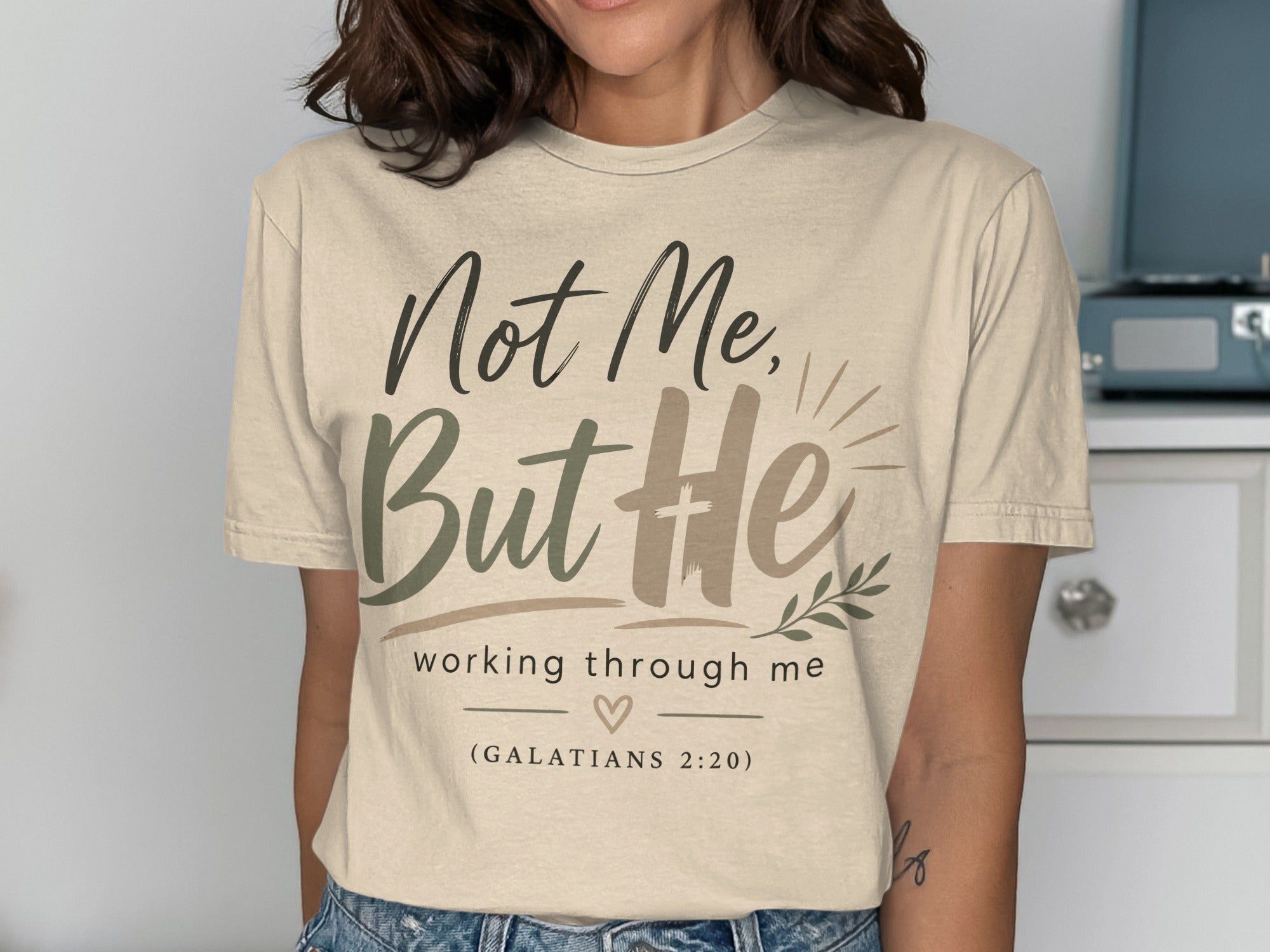 Cream t-shirt with "Not Me, But He" and Bible verse.