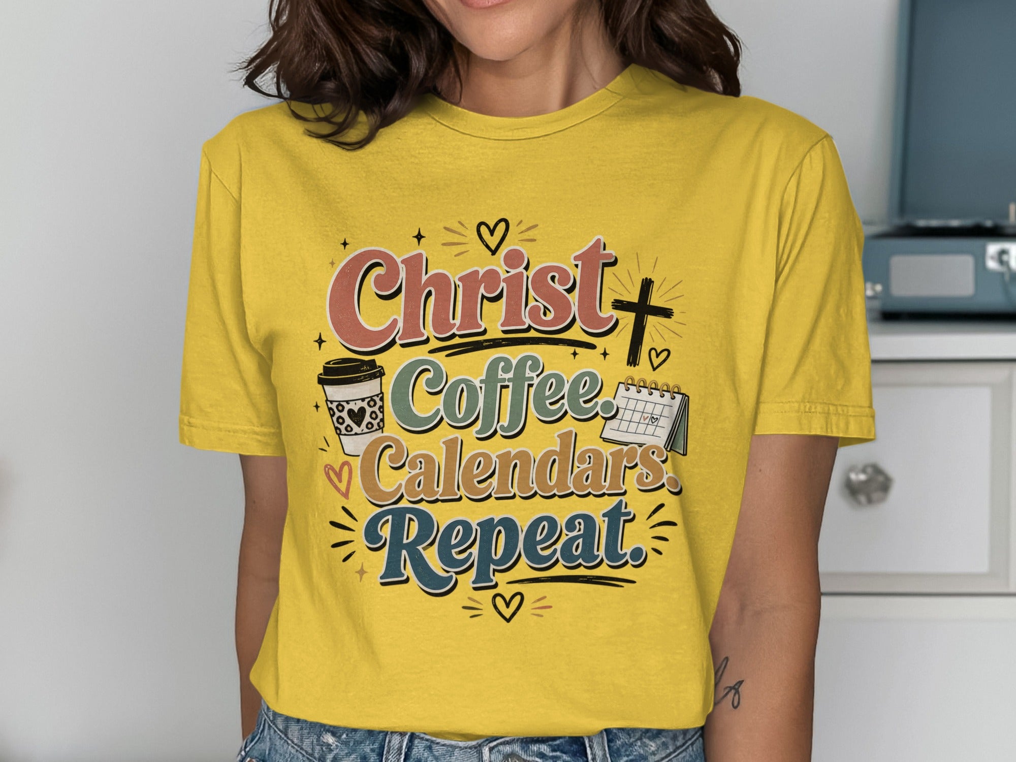 Yellow t-shirt with "Christ. Coffee. Calendars. Repeat." graphic and icons.