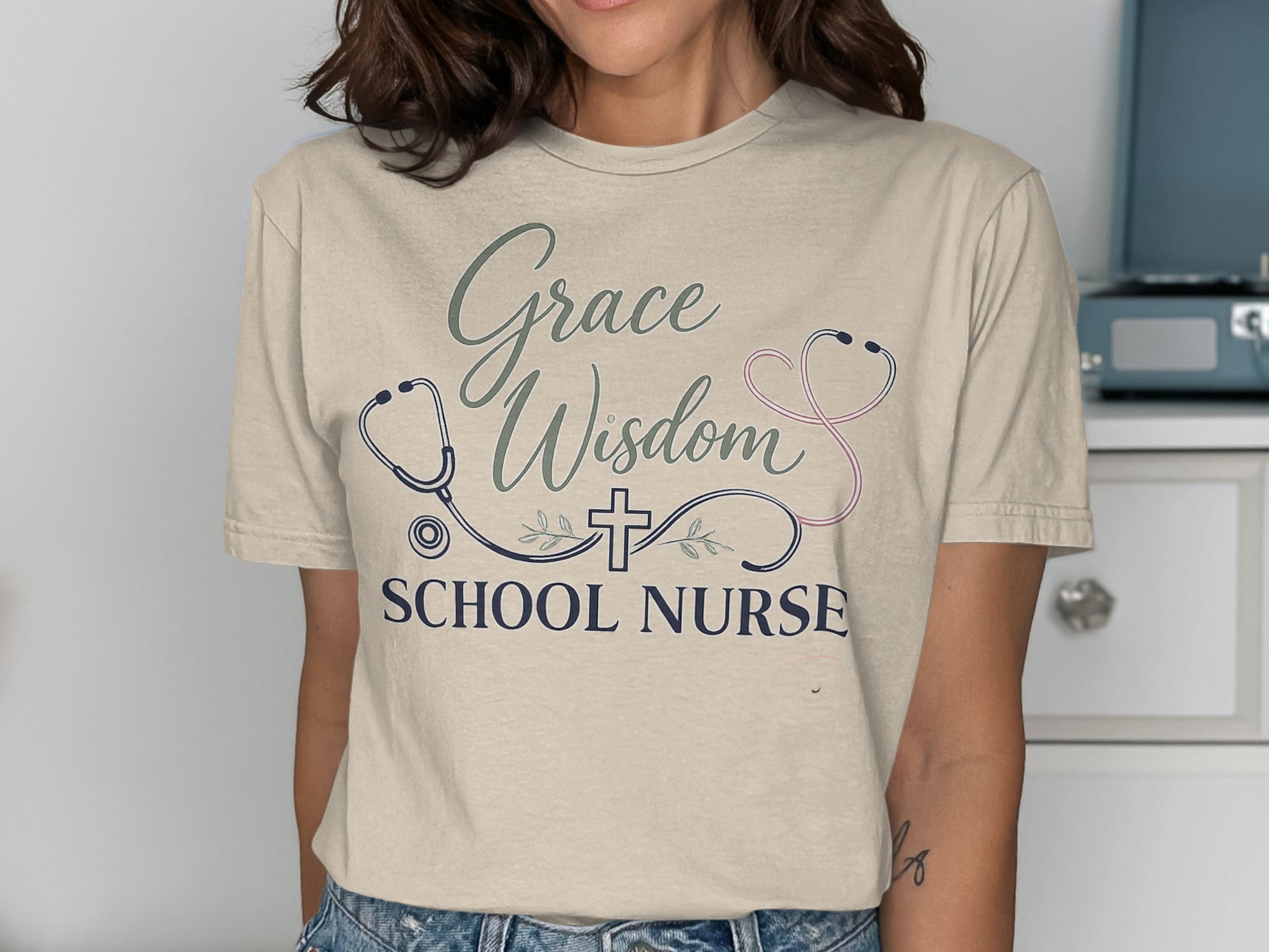 Cream t-shirt with "Grace Wisdom School Nurse" and stethoscope graphic.