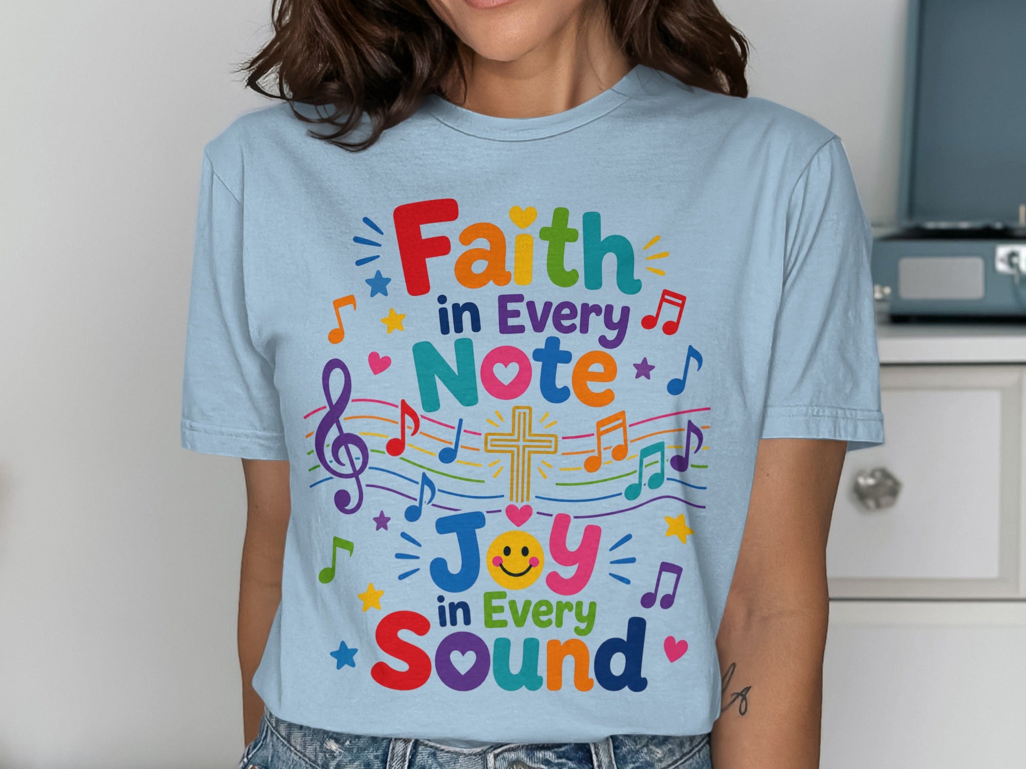 Light blue t-shirt with "Faith in Every Note, Joy in Every Sound" text and music notes.