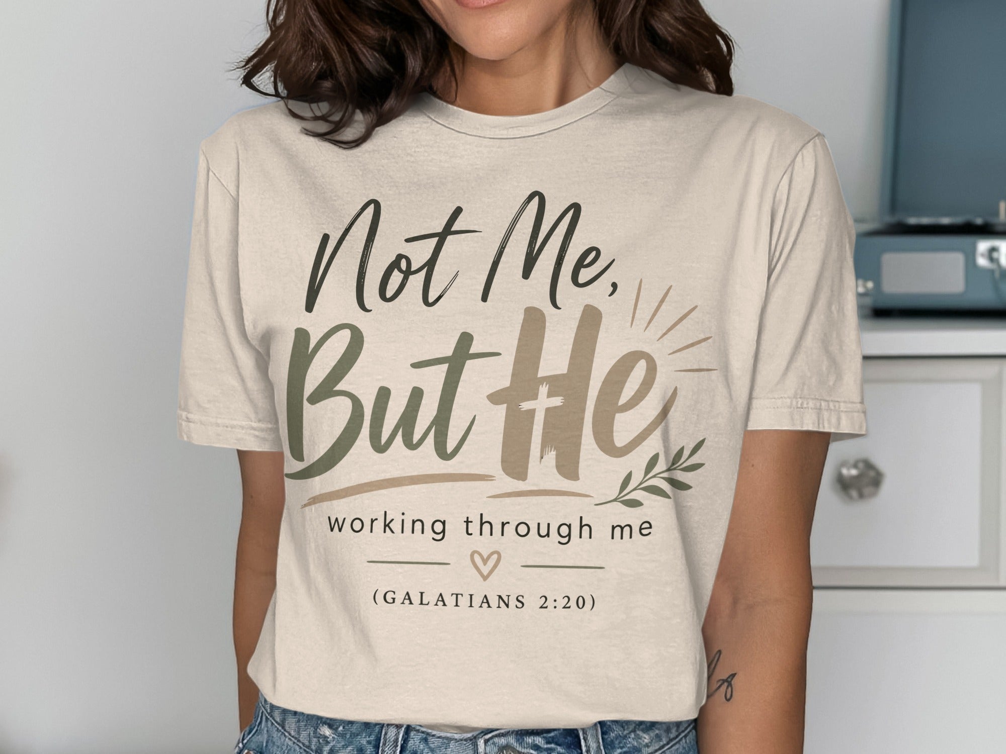 Cream t-shirt with "Not Me, But He working through me" text and a heart.