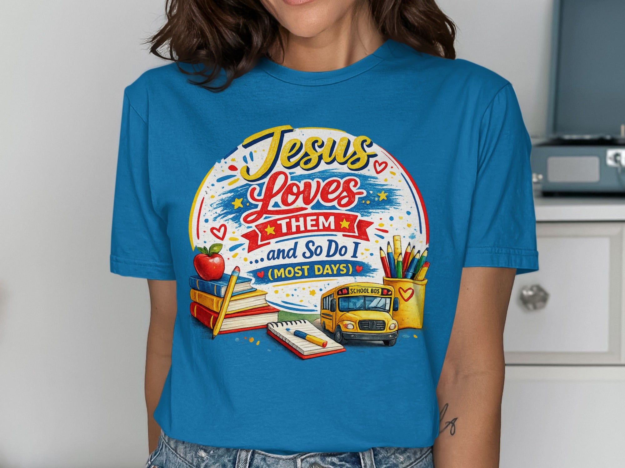 Blue t-shirt with "Jesus Loves Them... and So Do I" and school imagery.