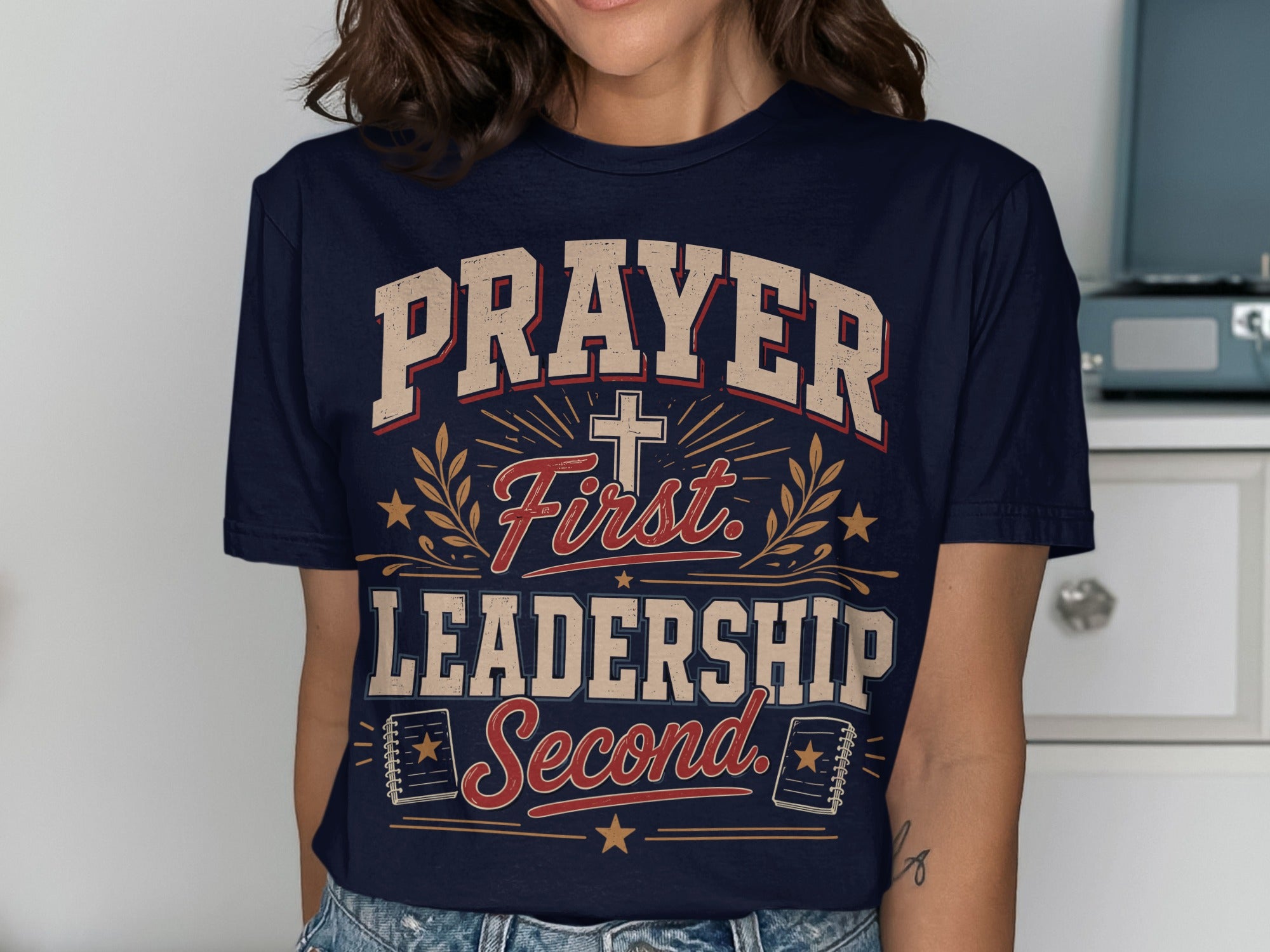 Navy t-shirt with "Prayer First, Leadership Second" text and cross graphic.