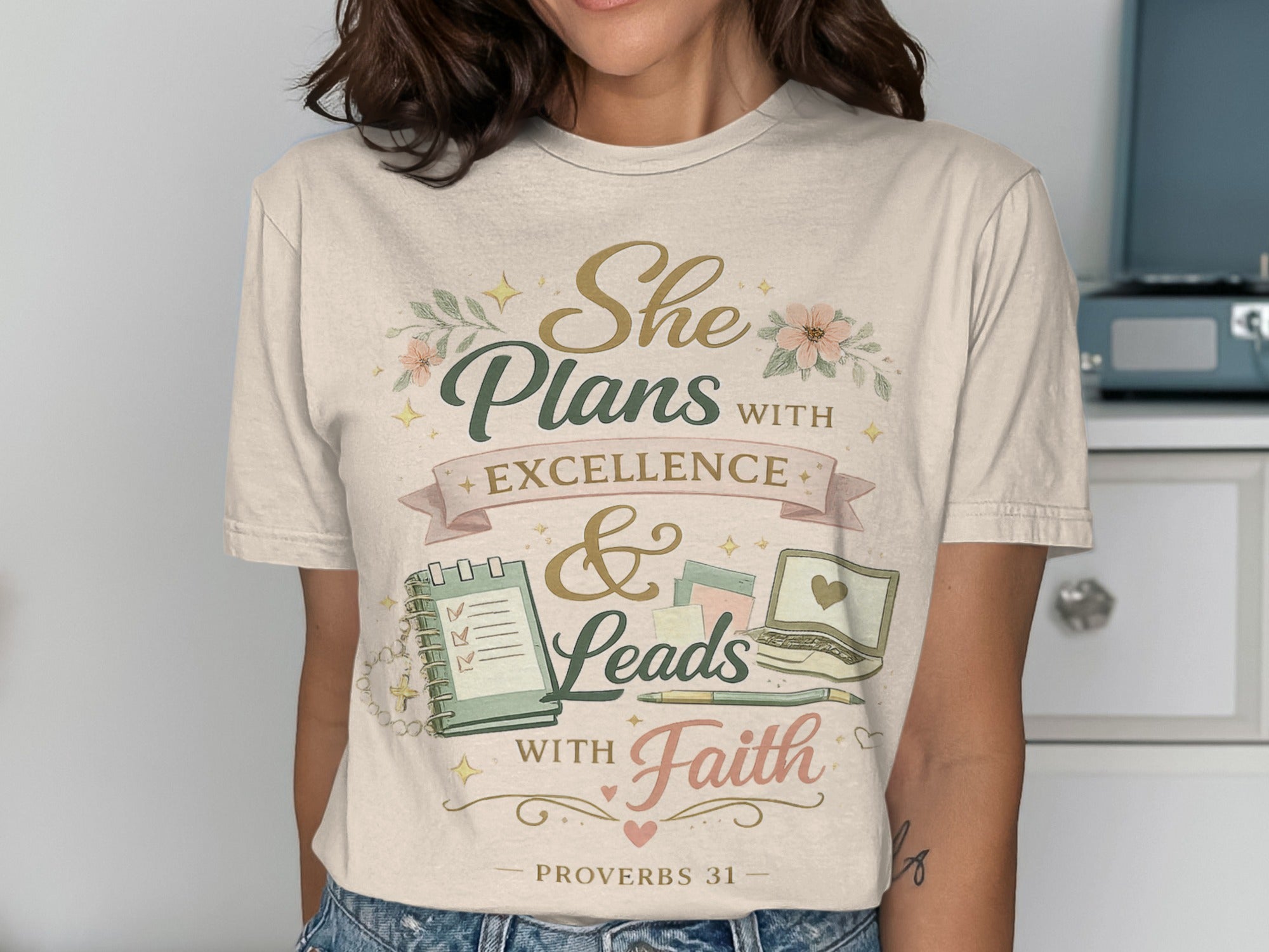 Woman wearing a t-shirt with "She Plans with Excellence & Leads with Faith" text.