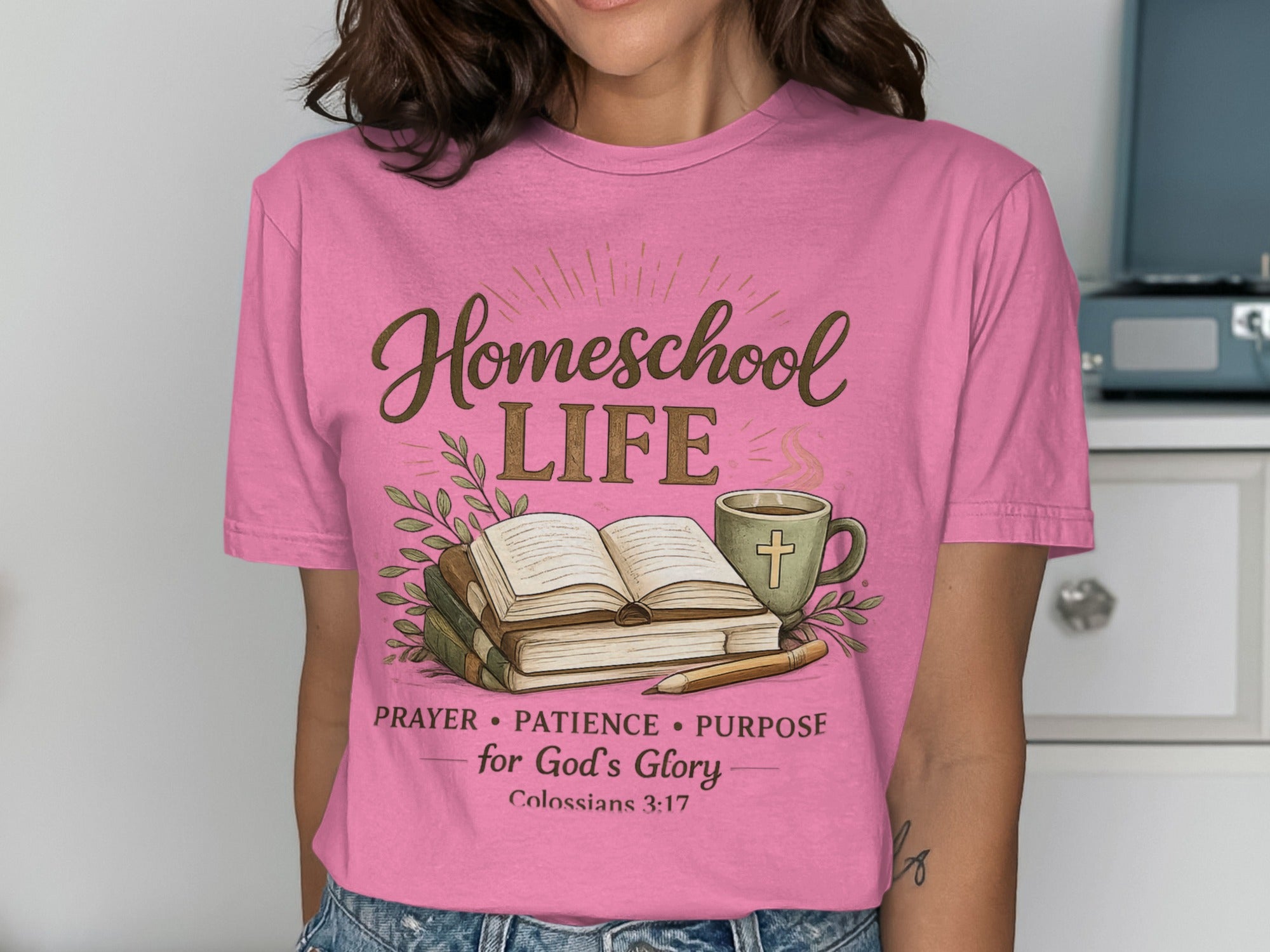 Pink t-shirt with "Homeschool LIFE" and Bible verse text over books and coffee cup.