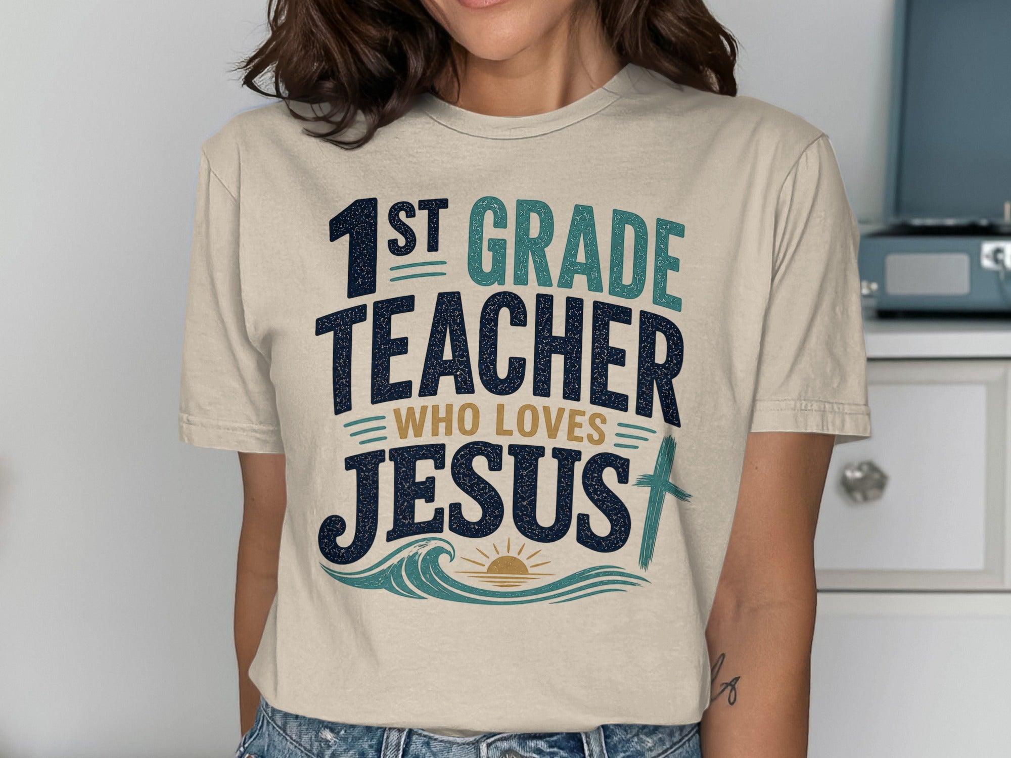 1st Grade Teacher who loves Jesus t-shirt with sun, waves, and cross graphic.