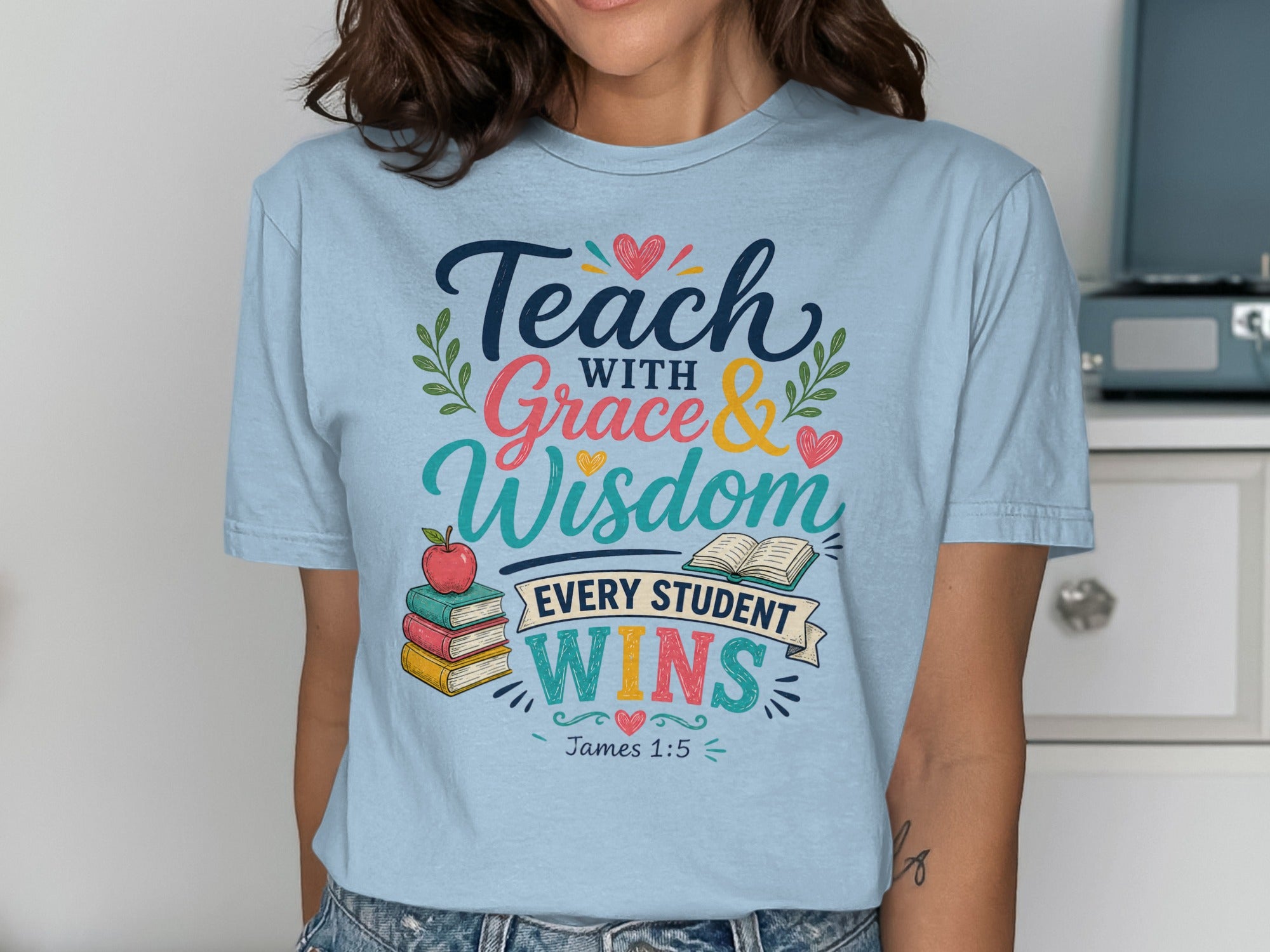 Light blue t-shirt with "Teach with Grace & Wisdom Every Student Wins" text and an apple.