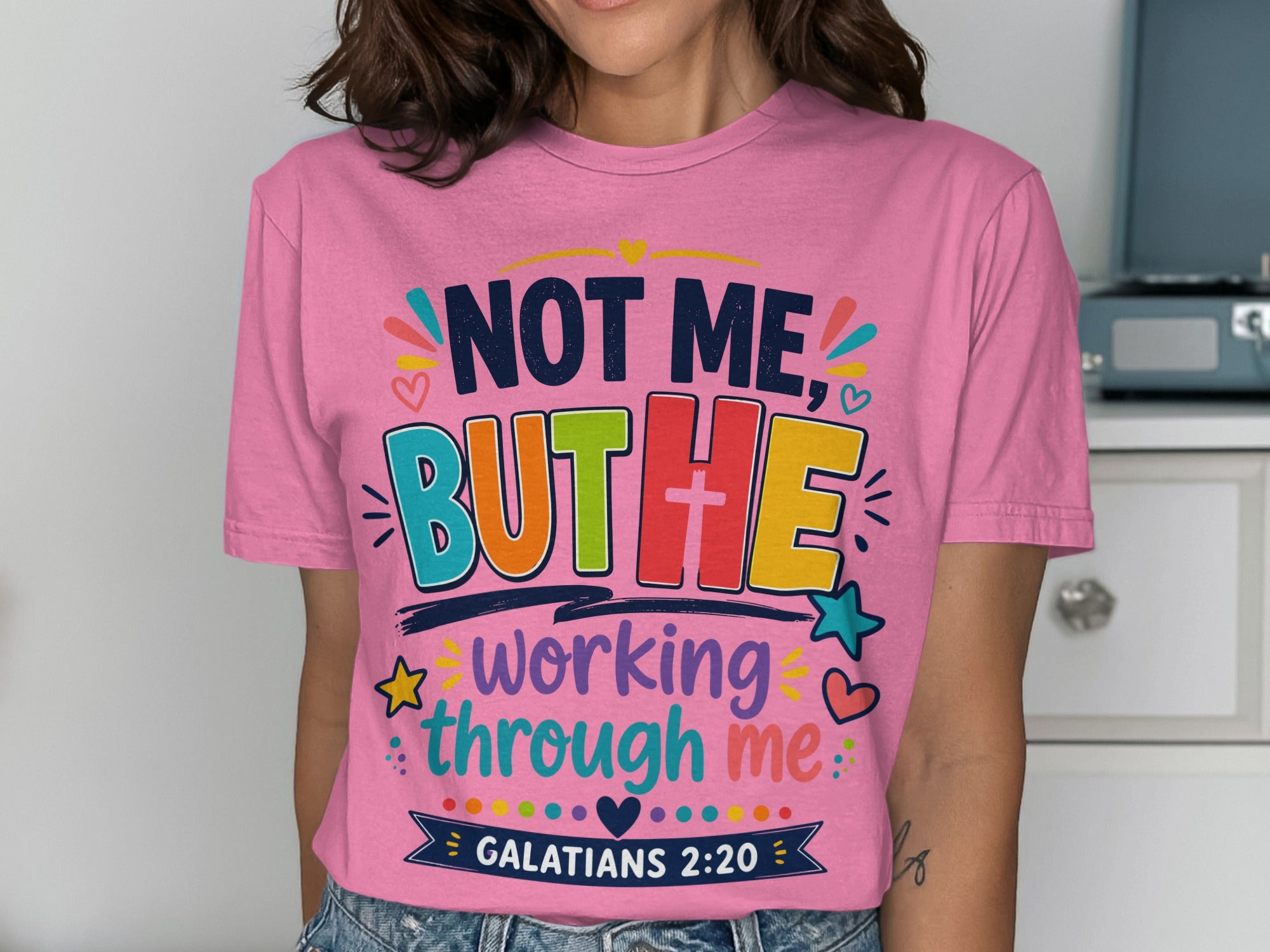 Pink t-shirt with colorful text "NOT ME, BUT THE working through me GALATIANS 2:20".