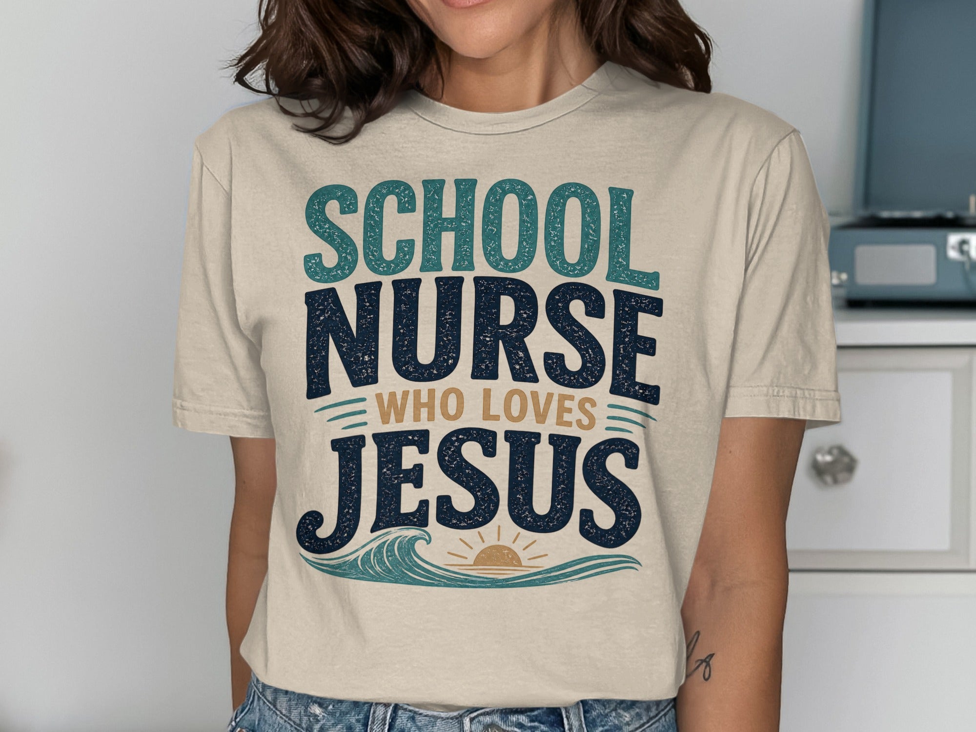 T-shirt with "School Nurse Who Loves Jesus" text and sun and waves graphic.