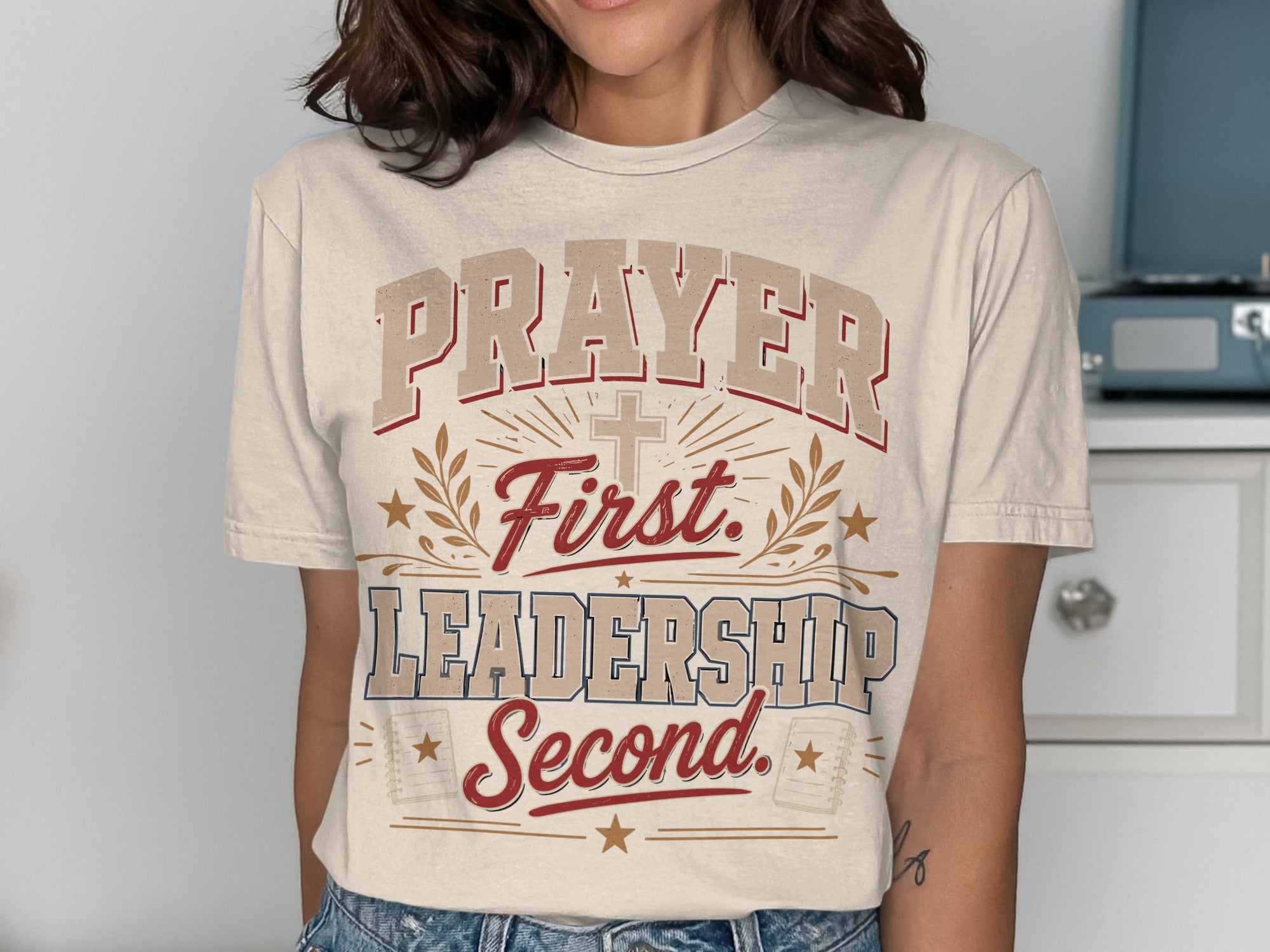 Cream t-shirt with "Prayer First. Leadership Second." text and cross graphic.