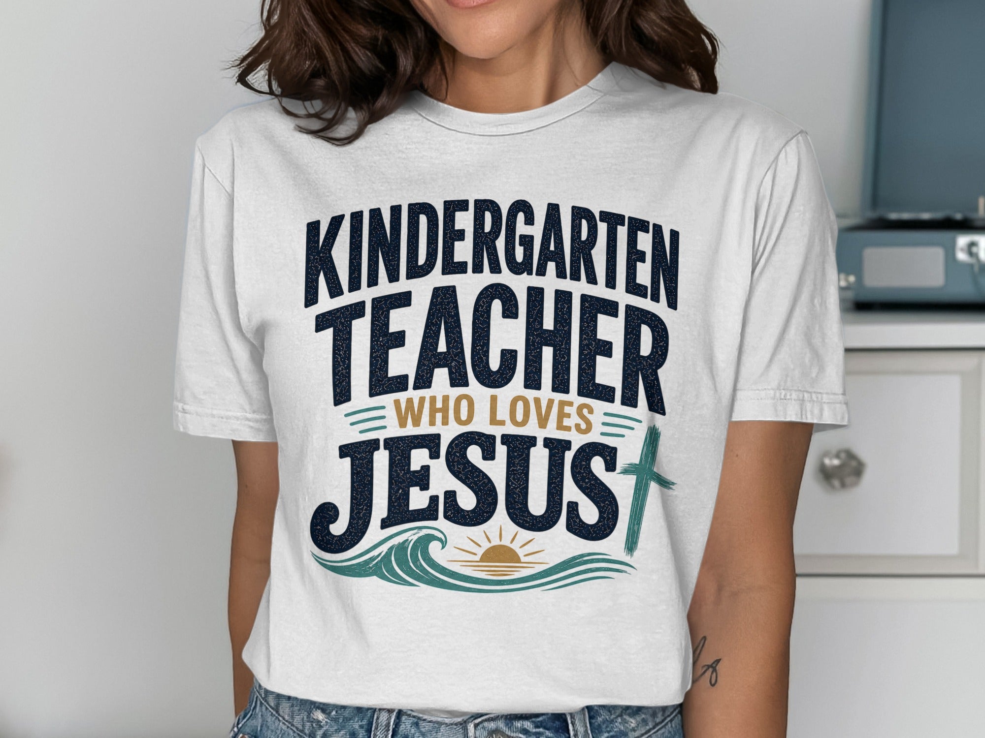 White t-shirt with text "Kindergarten Teacher Who Loves Jesus" and cross.
