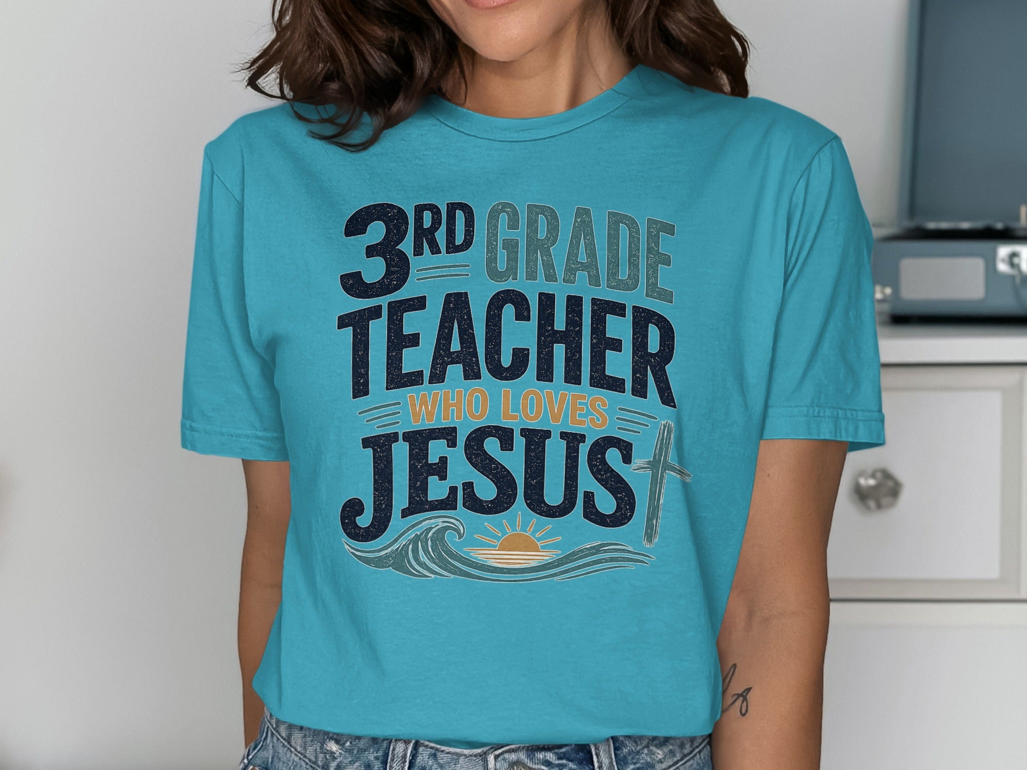 Teal t-shirt with "3rd GRADE TEACHER WHO LOVES JESUS" and a sun, waves, and cross.