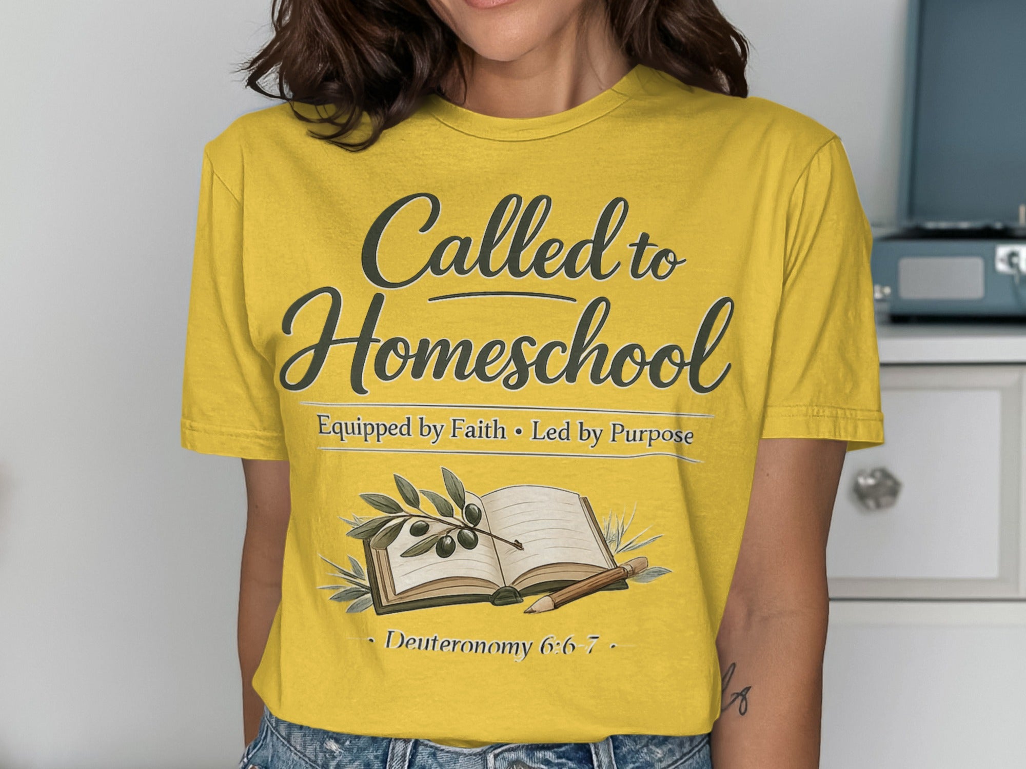 Yellow t-shirt with "Called to Homeschool" text, book, olive branch, and scripture.