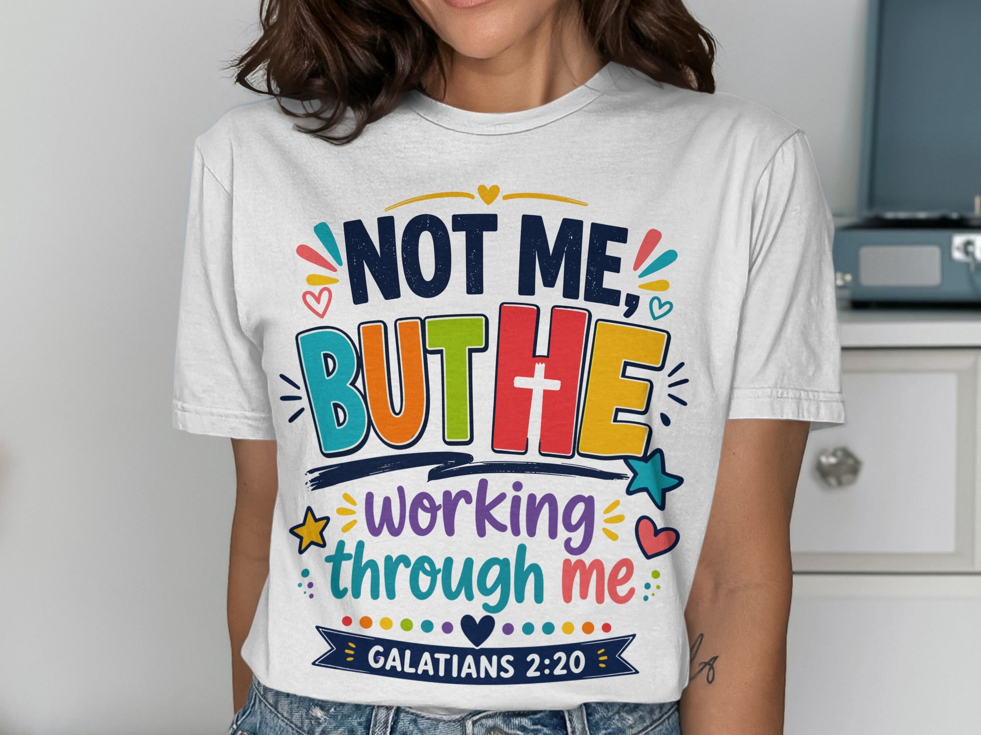 White t-shirt with "Not me, but he working through me. Galatians 2:20" text.