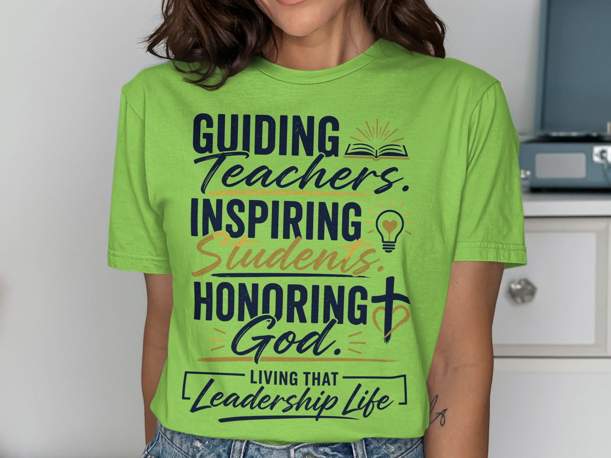 Green t-shirt with "Guiding Teachers, Inspiring Students, Honoring God" text.