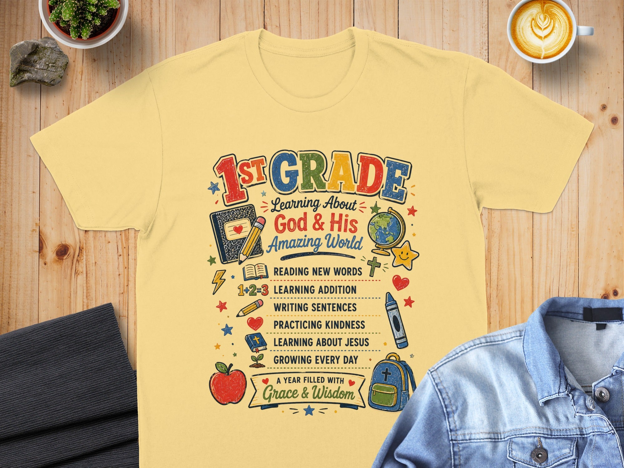 Yellow t-shirt with "1st Grade" and "God & His Amazing World" text and school-themed illustrations.