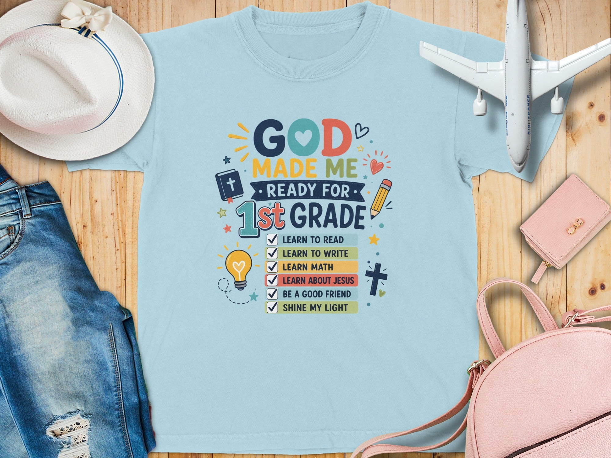 T-shirt reads "God Made Me Ready For 1st Grade" with school and faith-related tasks.