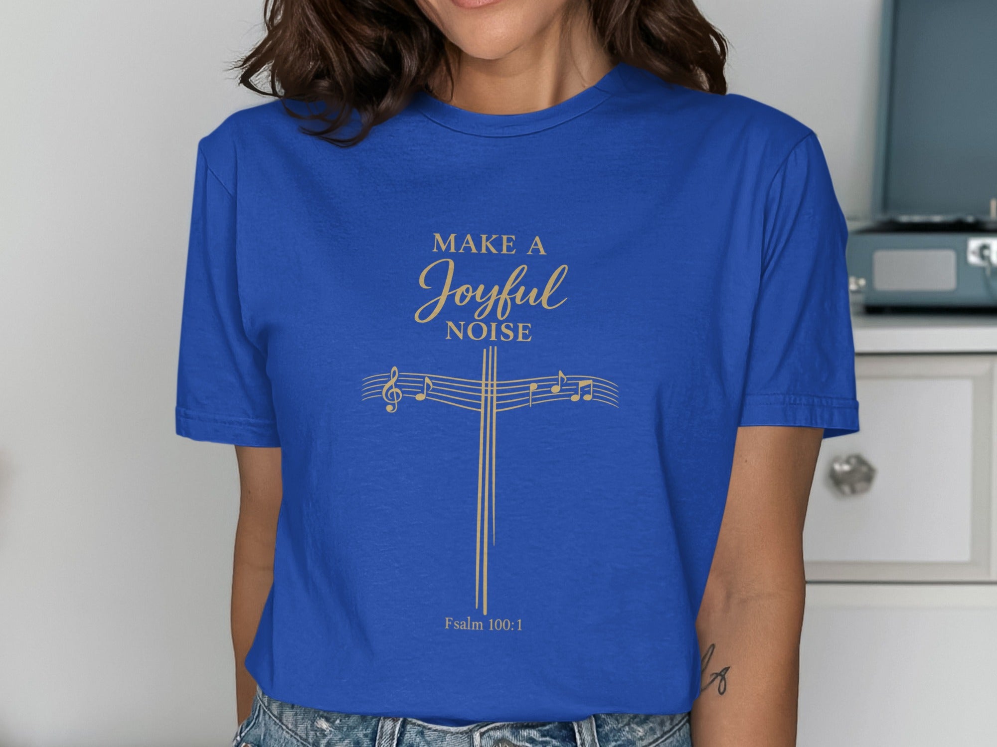 Blue t-shirt with "MAKE A JOYFUL NOISE" and musical notes on a cross.