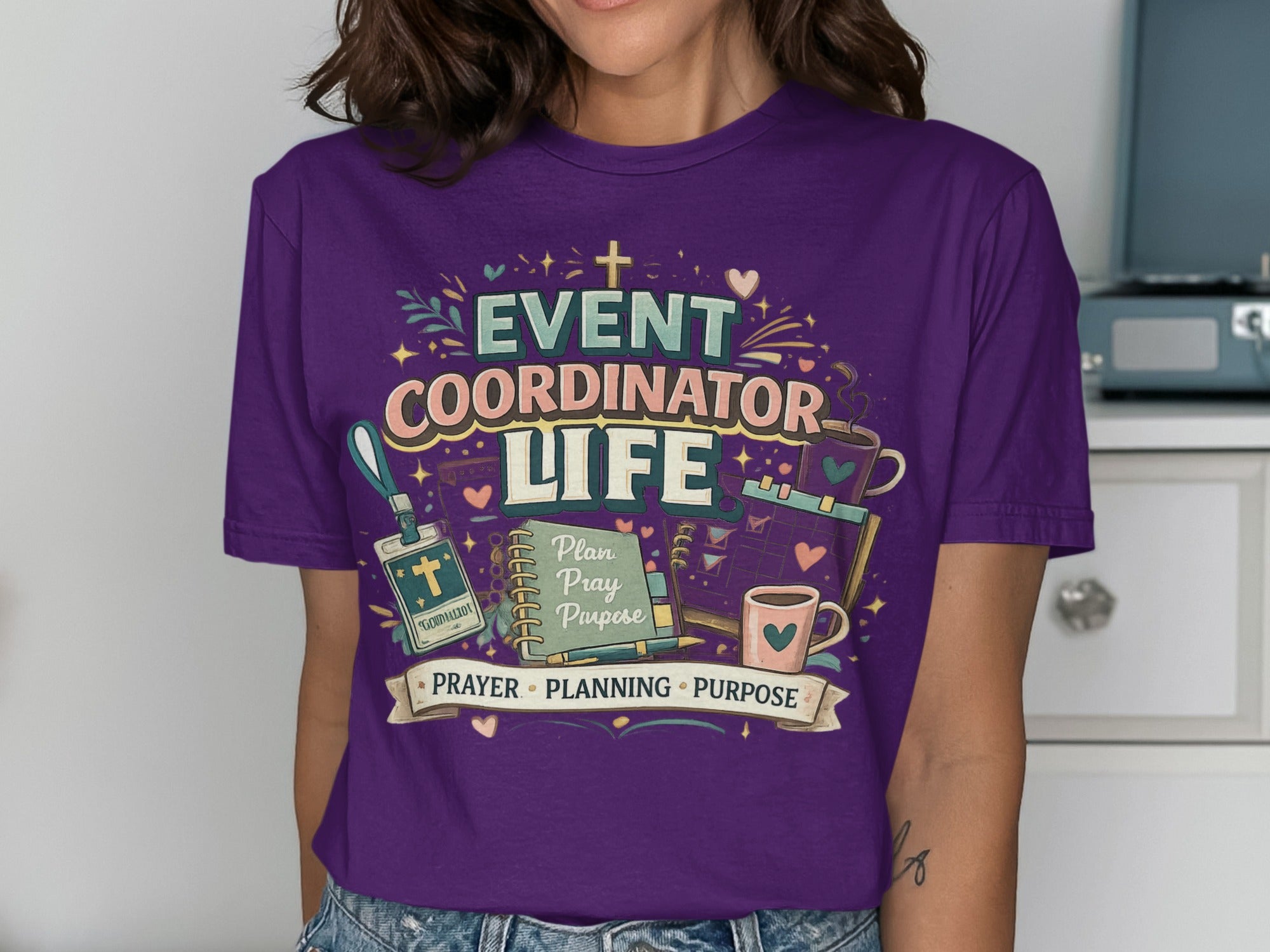 Purple t-shirt with "Event Coordinator Life" text, planner, and coffee cup.