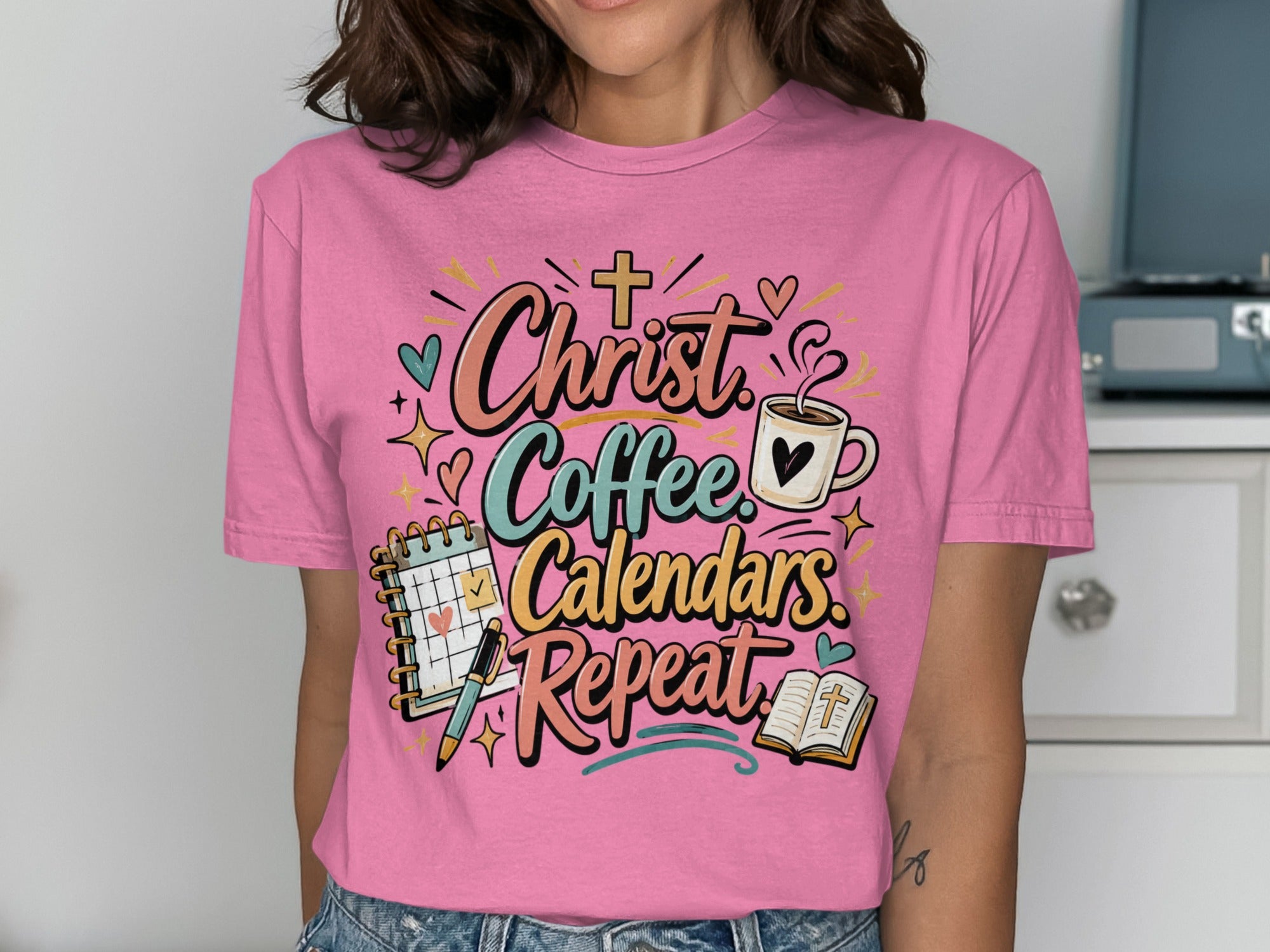 Pink t-shirt with "Christ Coffee Calendars Repeat" text and religious graphics.
