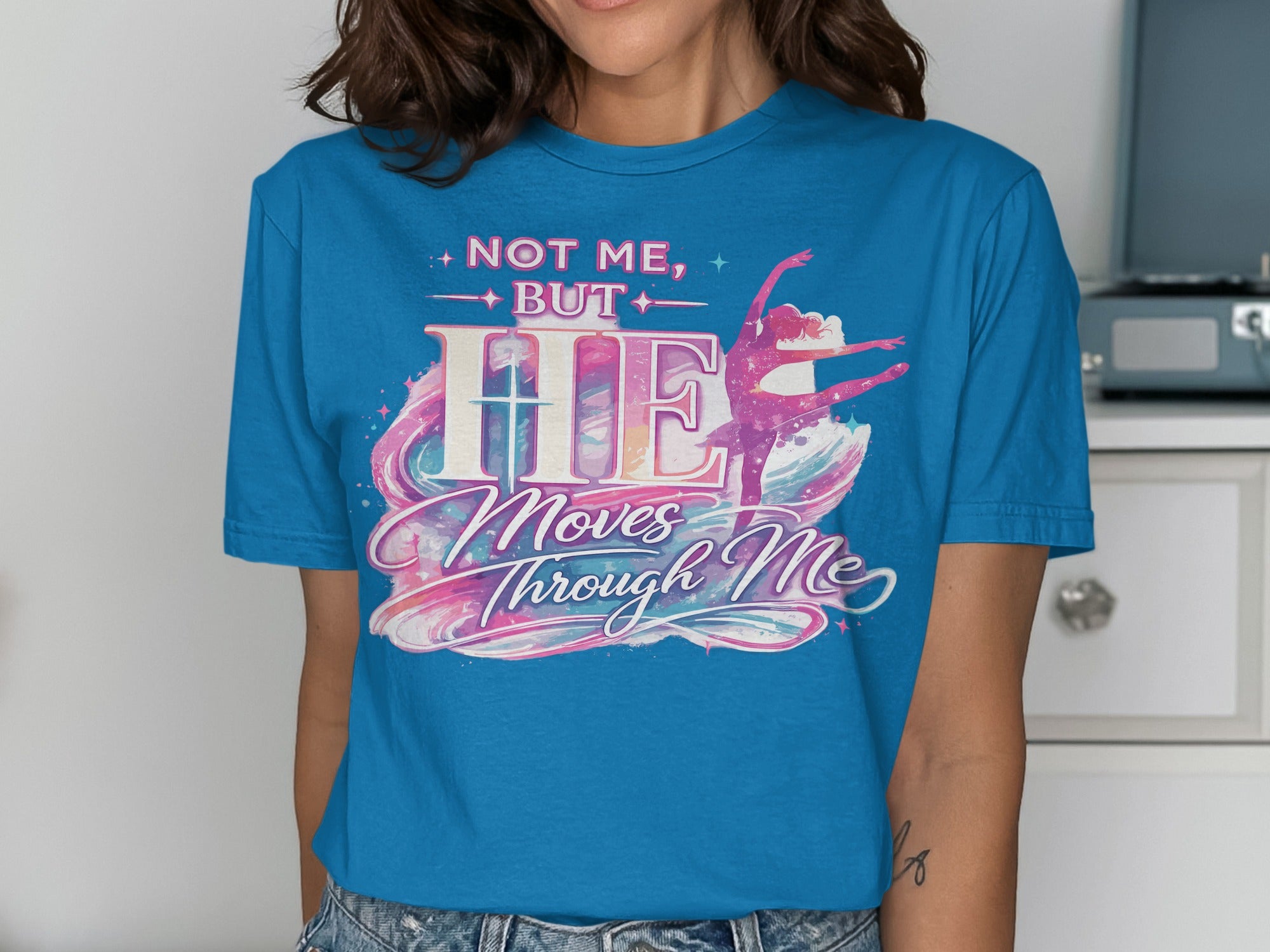 Blue t-shirt with "NOT ME, BUT HE Moves Through Me" and a dancing figure.